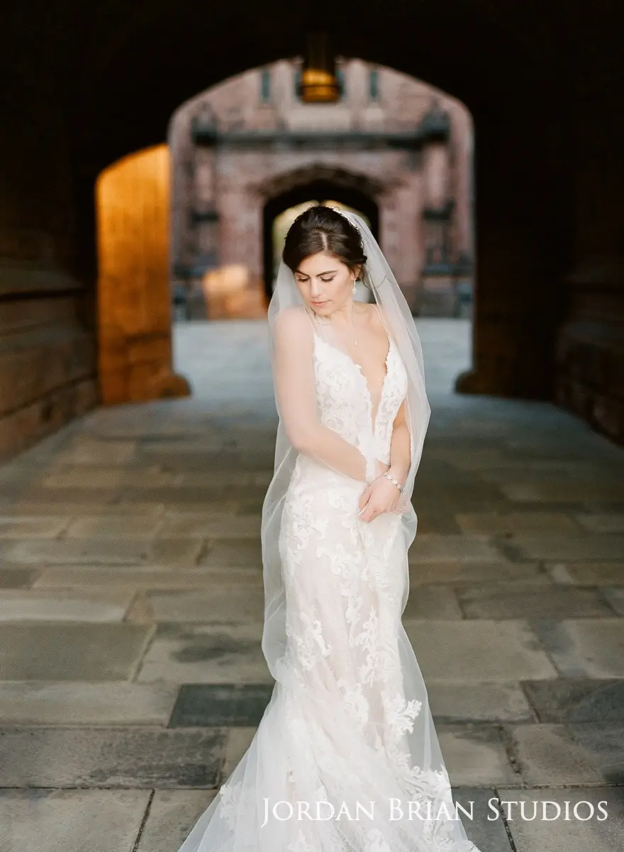 Bride wrapping veil around her posing wearing dress called Tuscany Lynette.