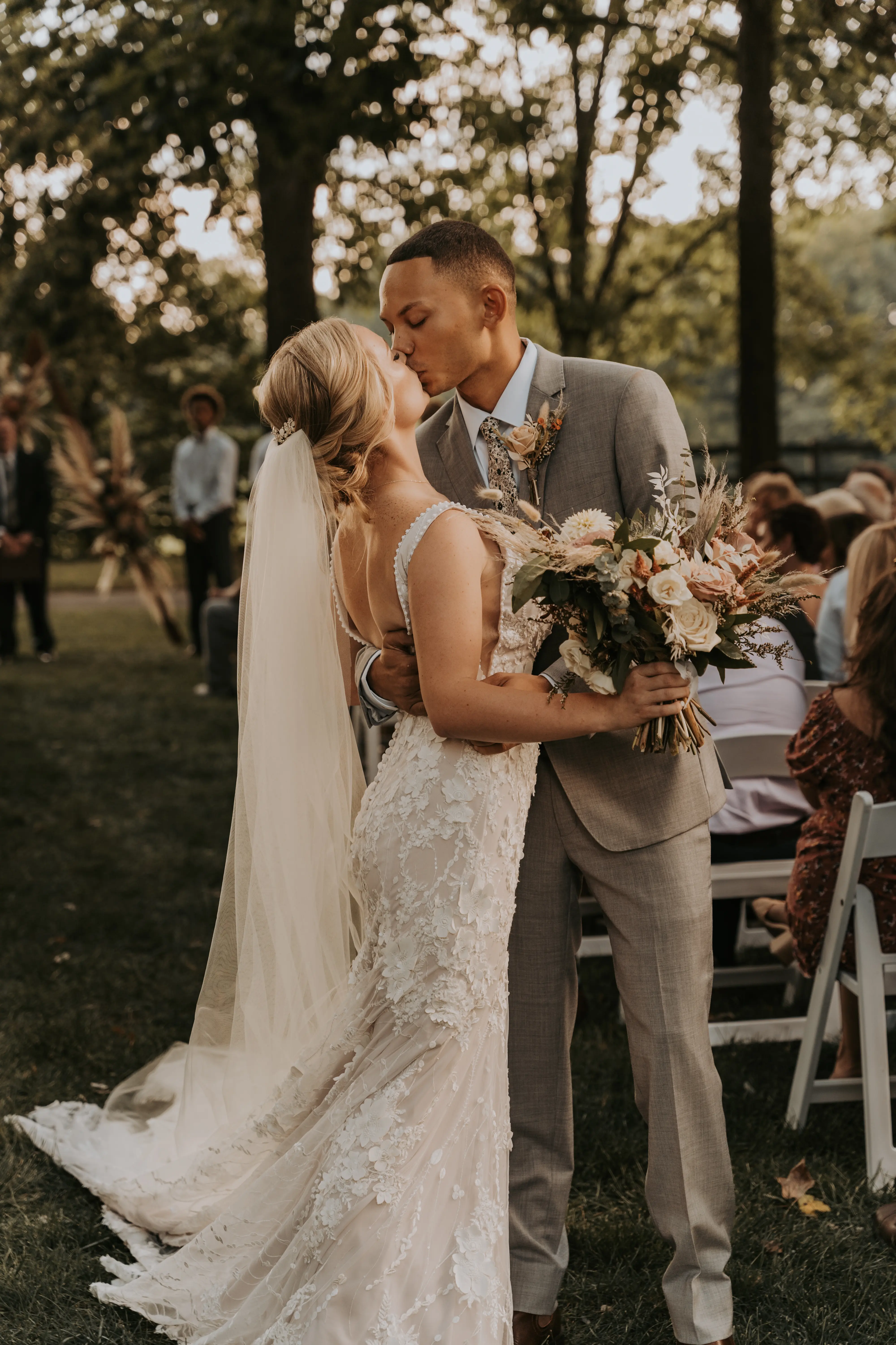 Groom Kissing Bride in Mermaid Wedding Dress with 3-D Floral Motifs and Extended Scalloped Lace Train Called Cruz by Sottero & Midgley