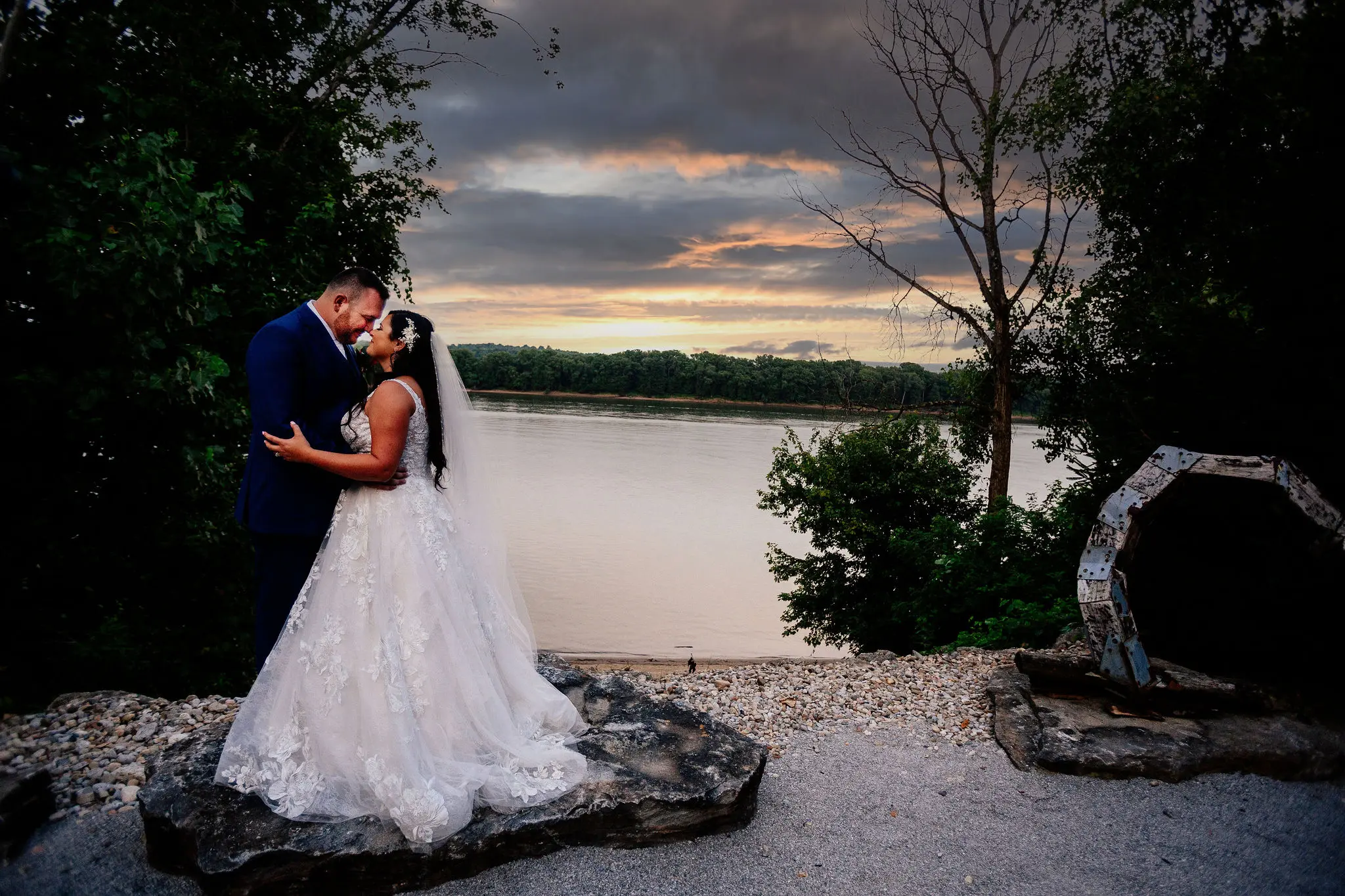 Bride and groom by lake at sunset.