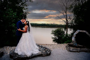 Bride and groom by lake at sunset.