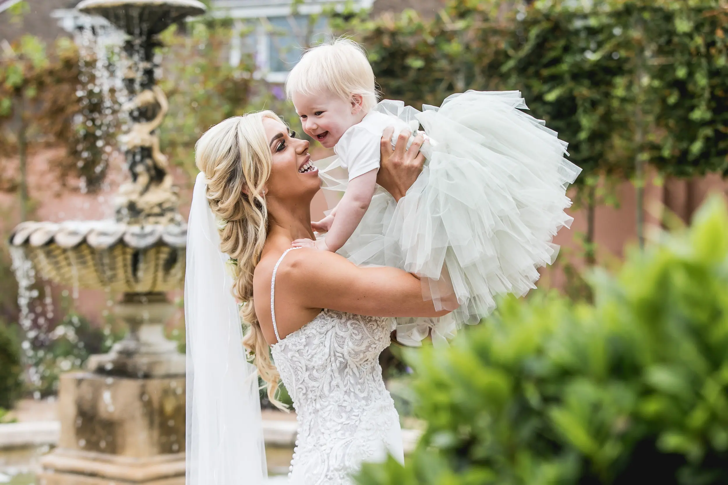 Bride holding baby flower girl joyfully up in the air.