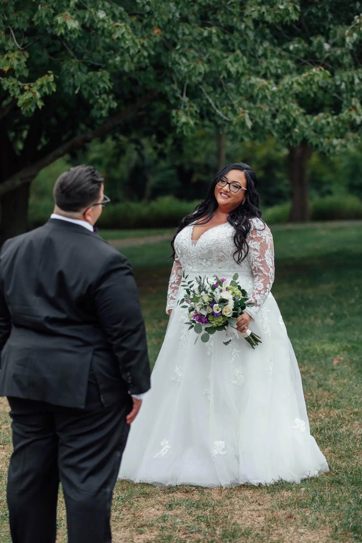 Bride Wearing Vintage Royalty Long Sleeve Wedding Dress Called Raphael By Maggie Sottero Gazing At Groom Holding Floral Bouquet