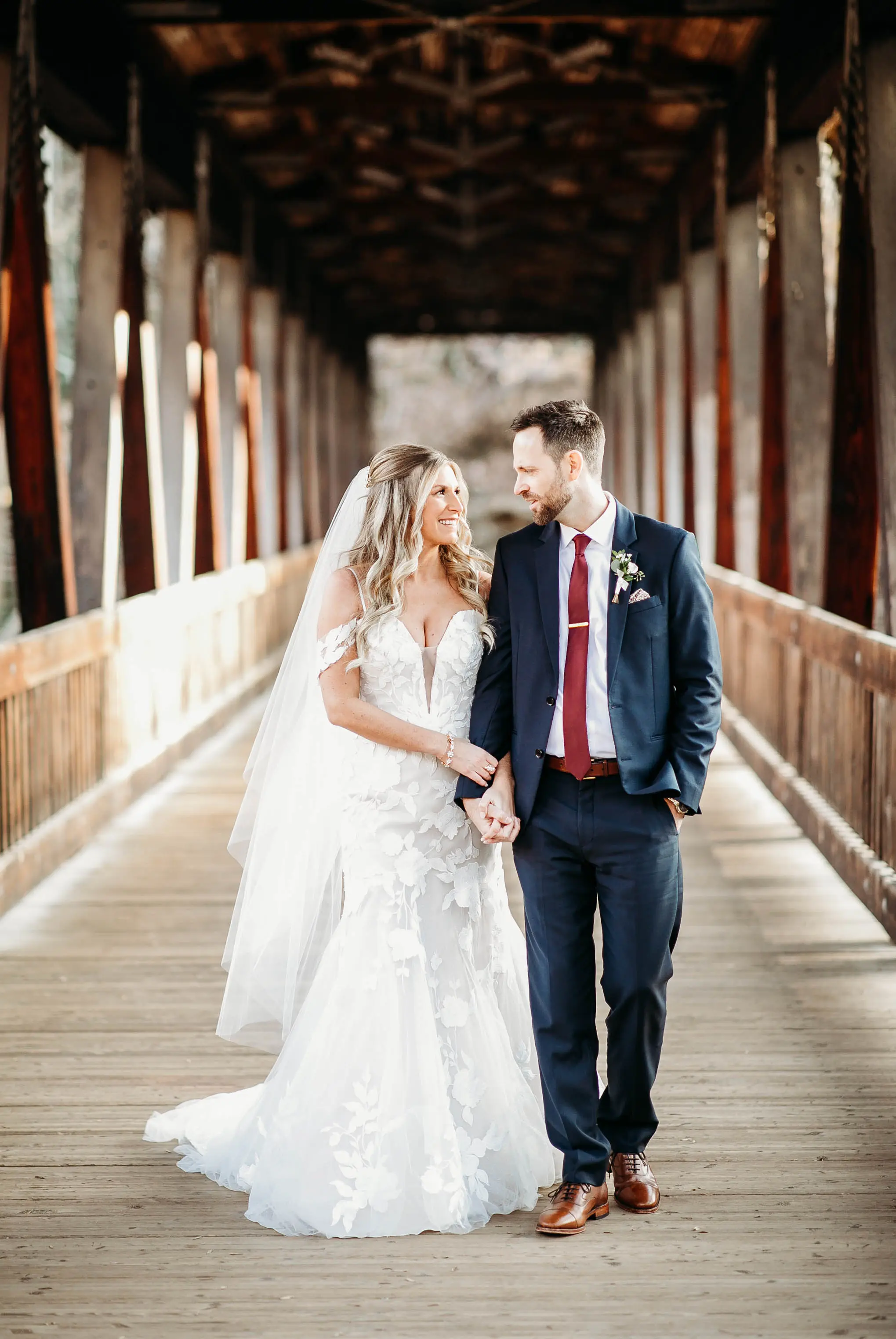 Bride And Groom Standing Together. Bride Wearing Mermaid Wedding Dress With Oversized Lace Called Hattie By Rebecca Ingram