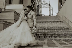 Bride Wearing Tiered Princess Skirt Wedding Dress Called Yasmin By Maggie Sottero With Groom In Front Of Stairs