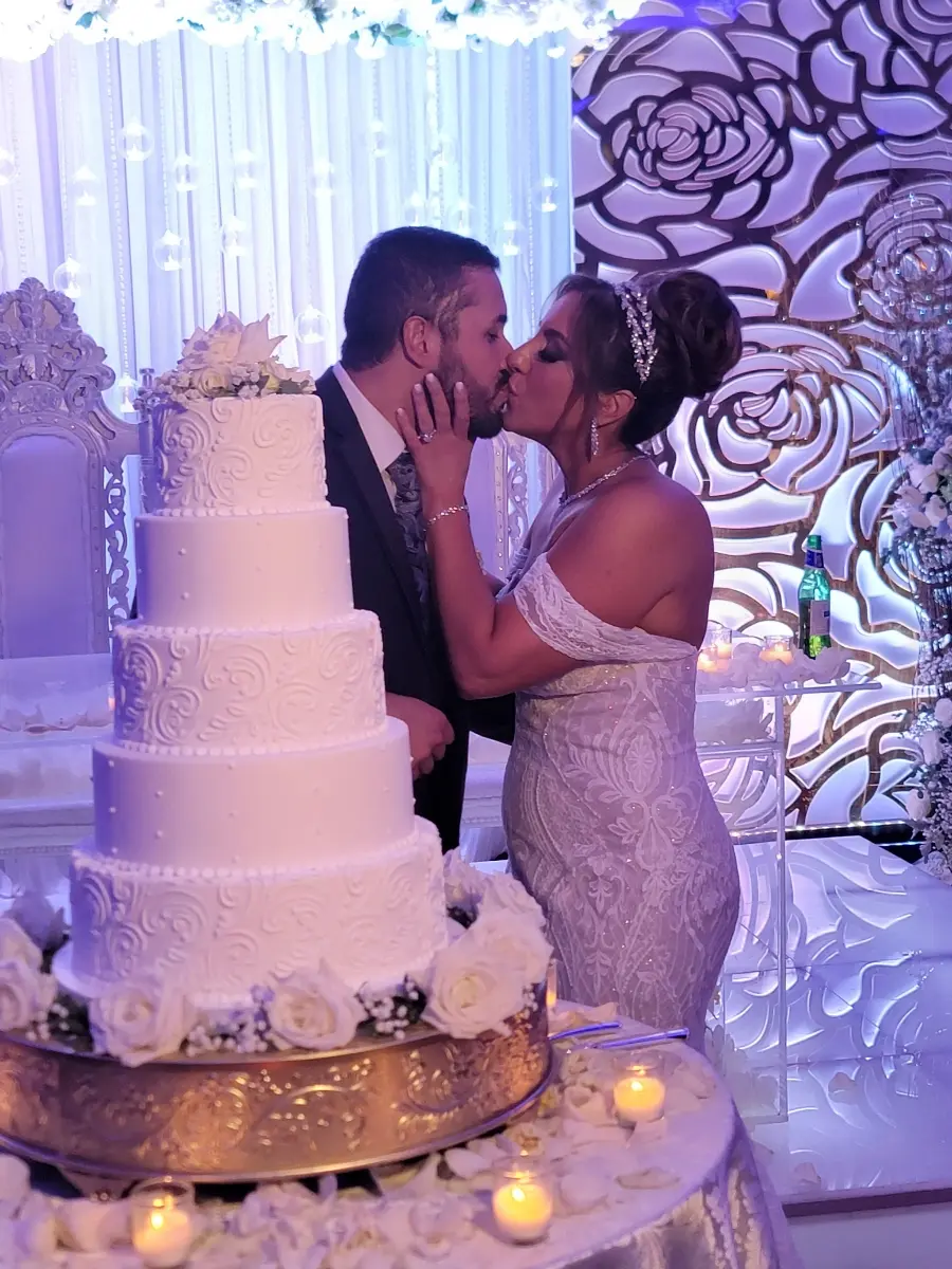 Bride wearing Bronson wedding dress by Sottero and Midgley kissing her husband with their wedding cake