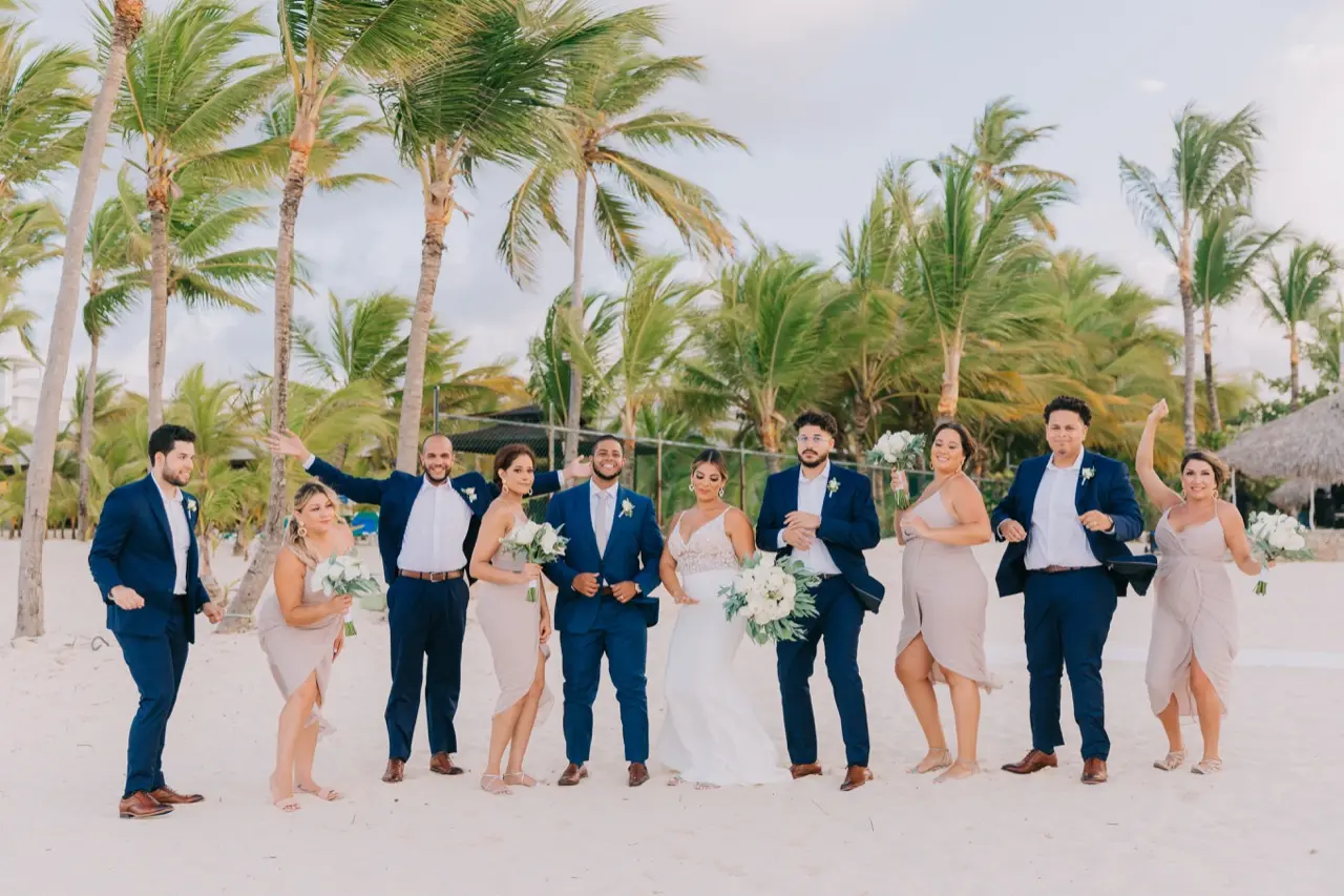 Wedding party at beach wedding wit palm trees behind them.