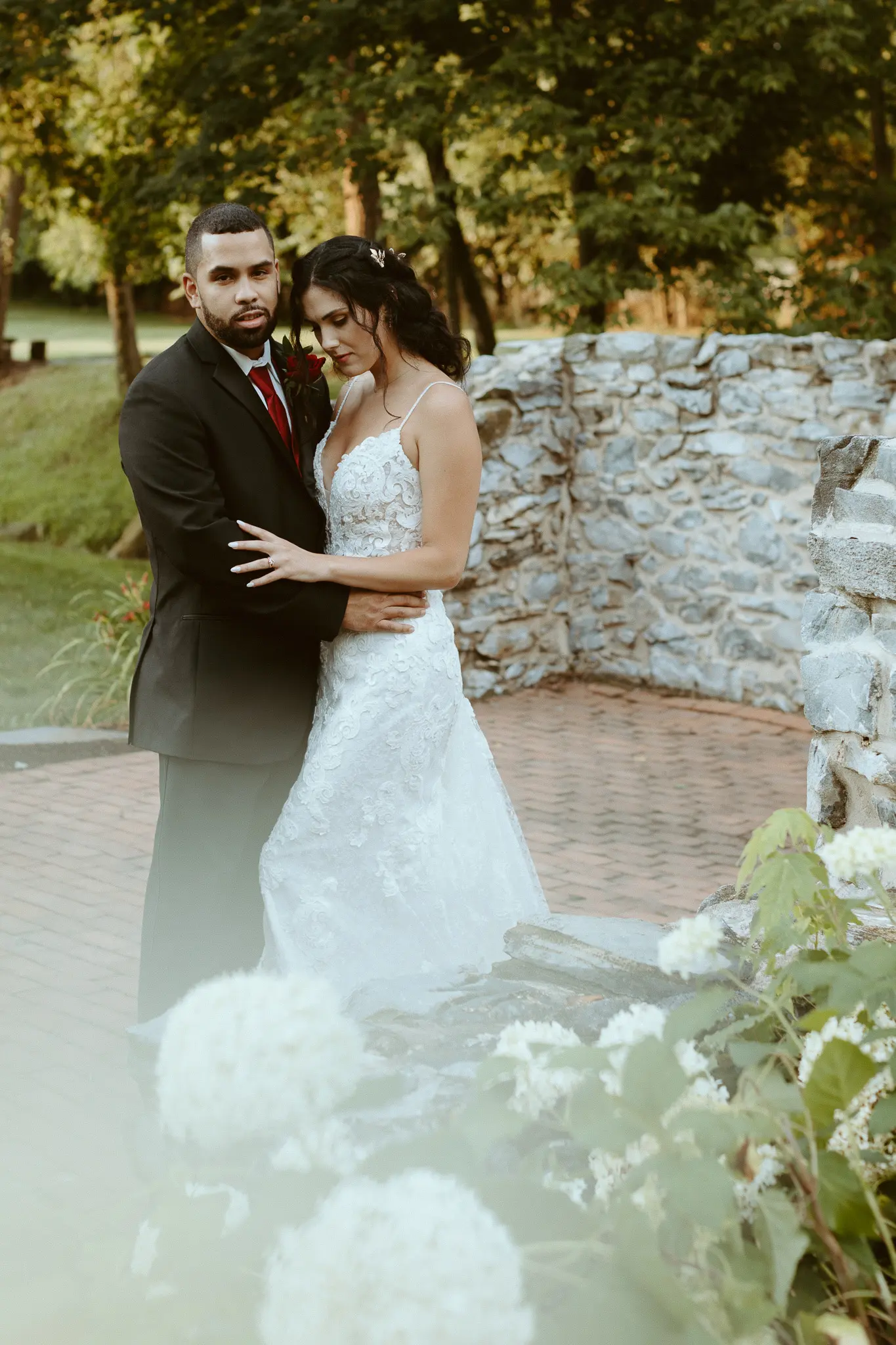 Bride with groom wearing lace sheath wedding dress.