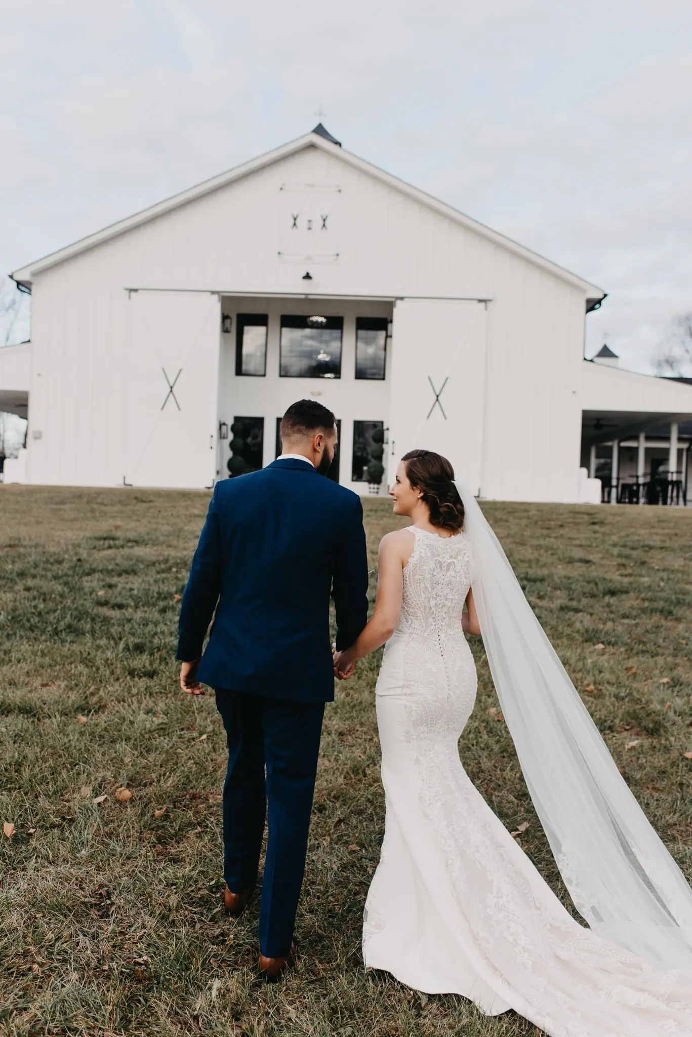 Bride and Groom Walk Together. Bride Wearing Halter Lace Detailer Fit And Flare Wedding Dress Called Kevyn By Sottero And Midgley And A Long Veil