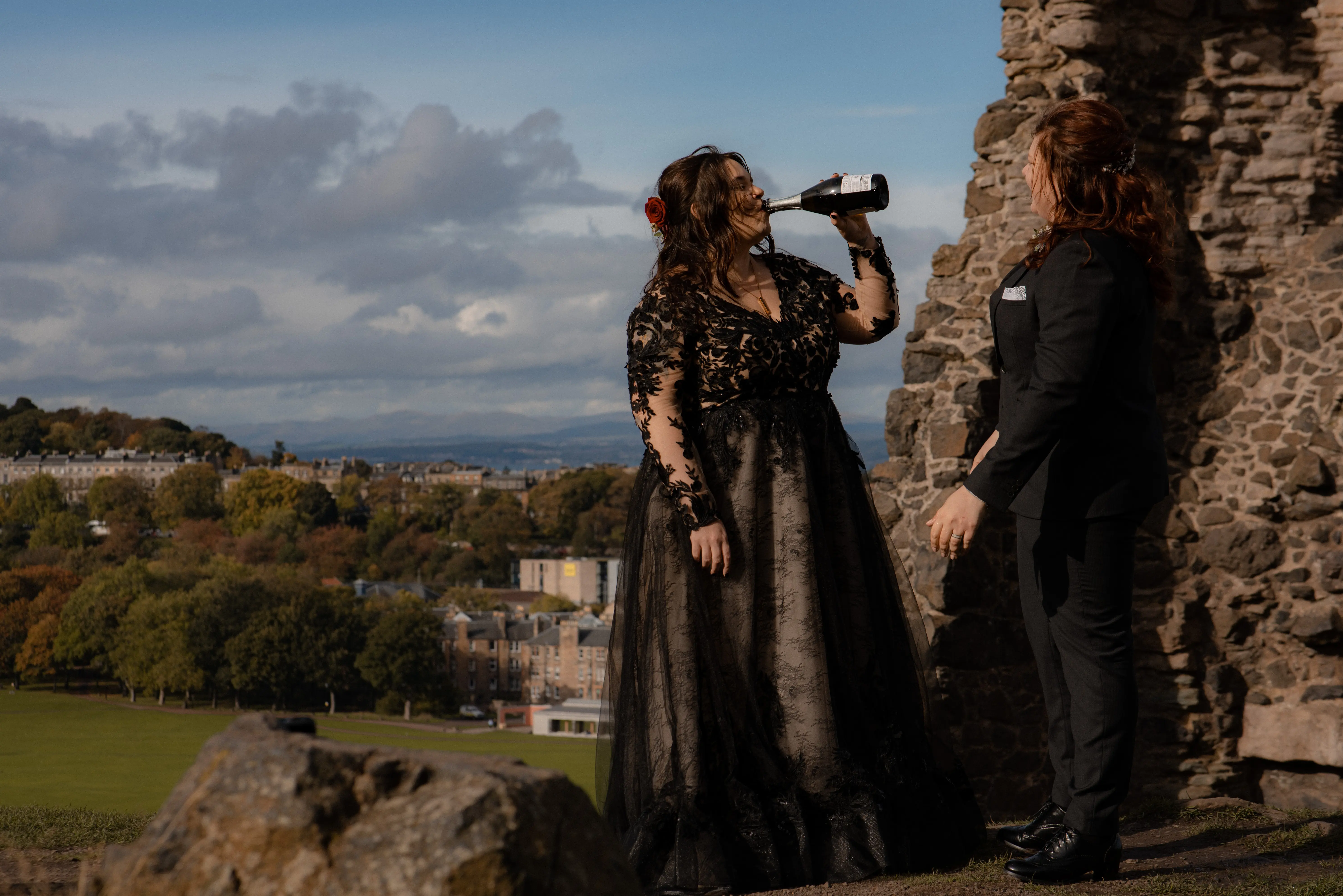 Bride Wearing Black A-Line Wedding Dress Called Zander By Sottero And Midgley Drinking Wine With Wife