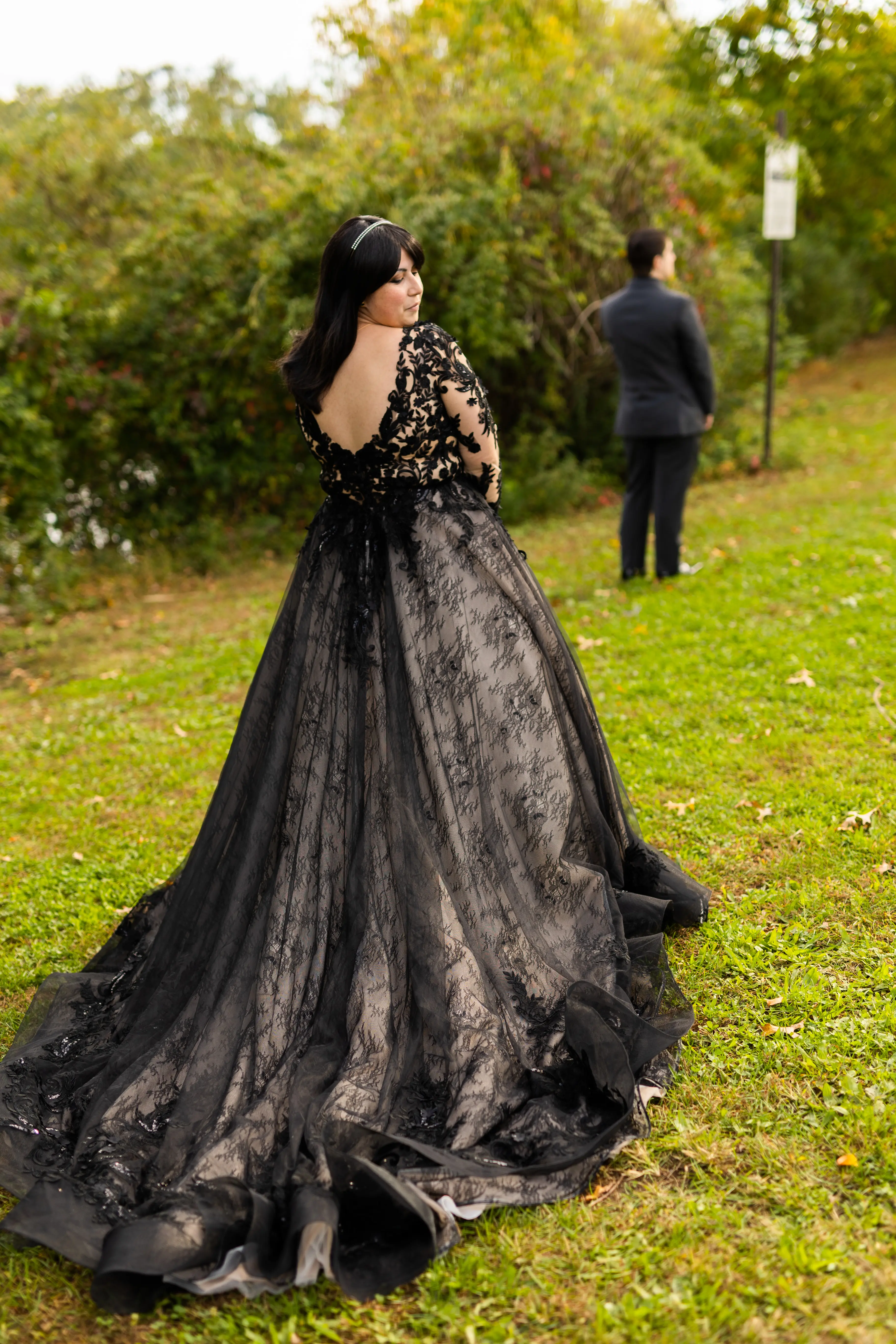 Bride in a Field Wearing Long Sleeve Black Lace Ballgown Wedding Dress Walking to Groom.