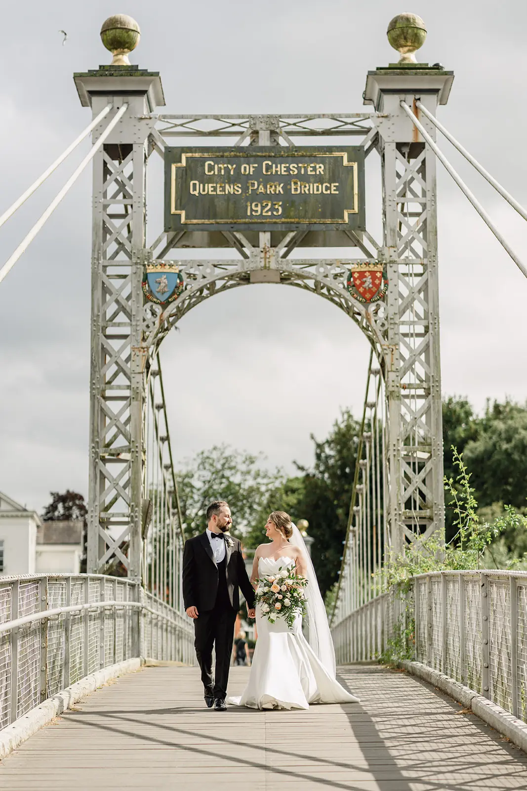 Bride Wearing Modern Wedding Dress Called Marilyn By Sottero And Midgley Walking With Groom On A Bridge