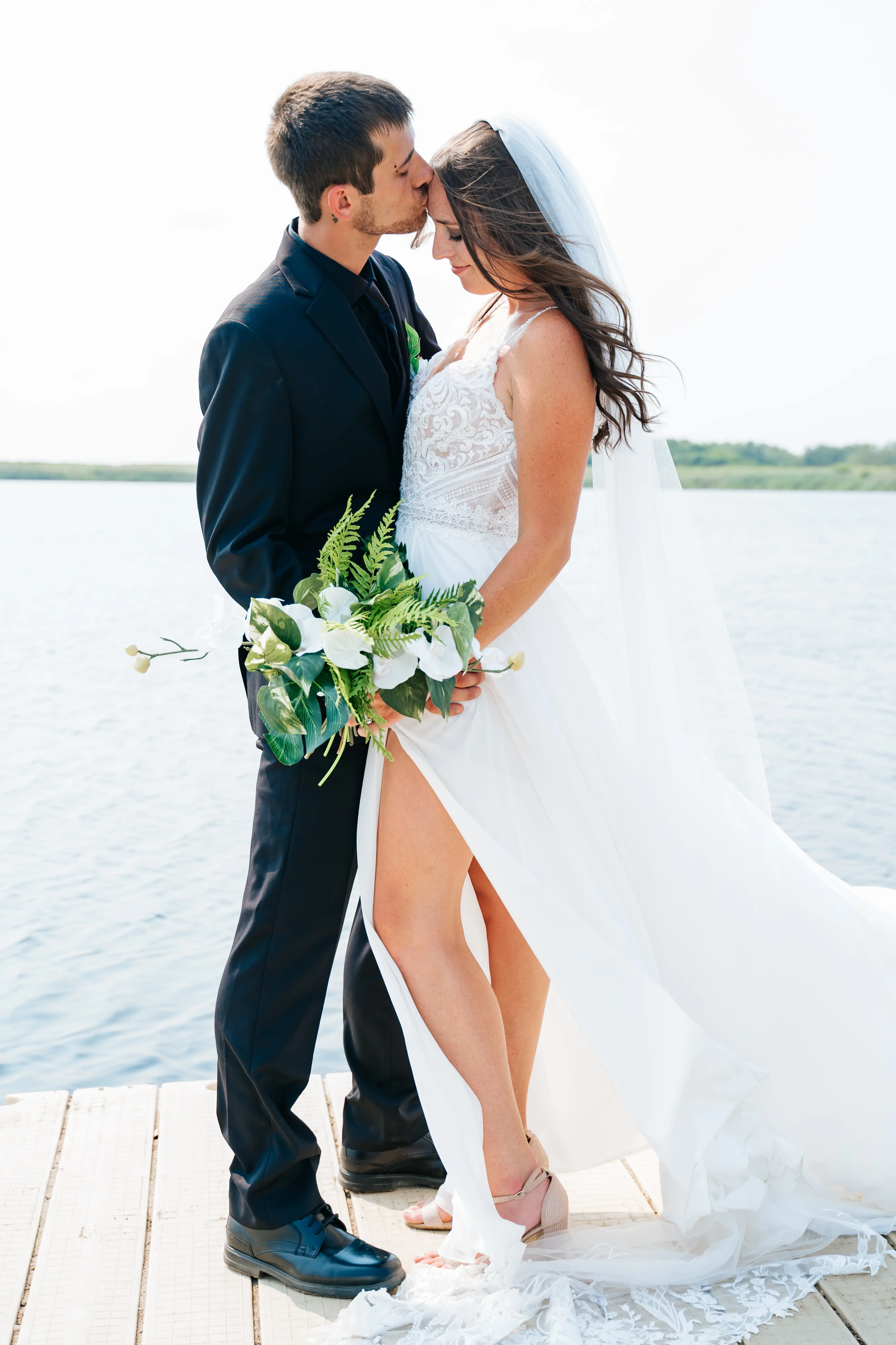 Bride Wearing Beach Sheath Wedding Dress Called Lorraine By Rebecca Ingram With Groom On A Dock