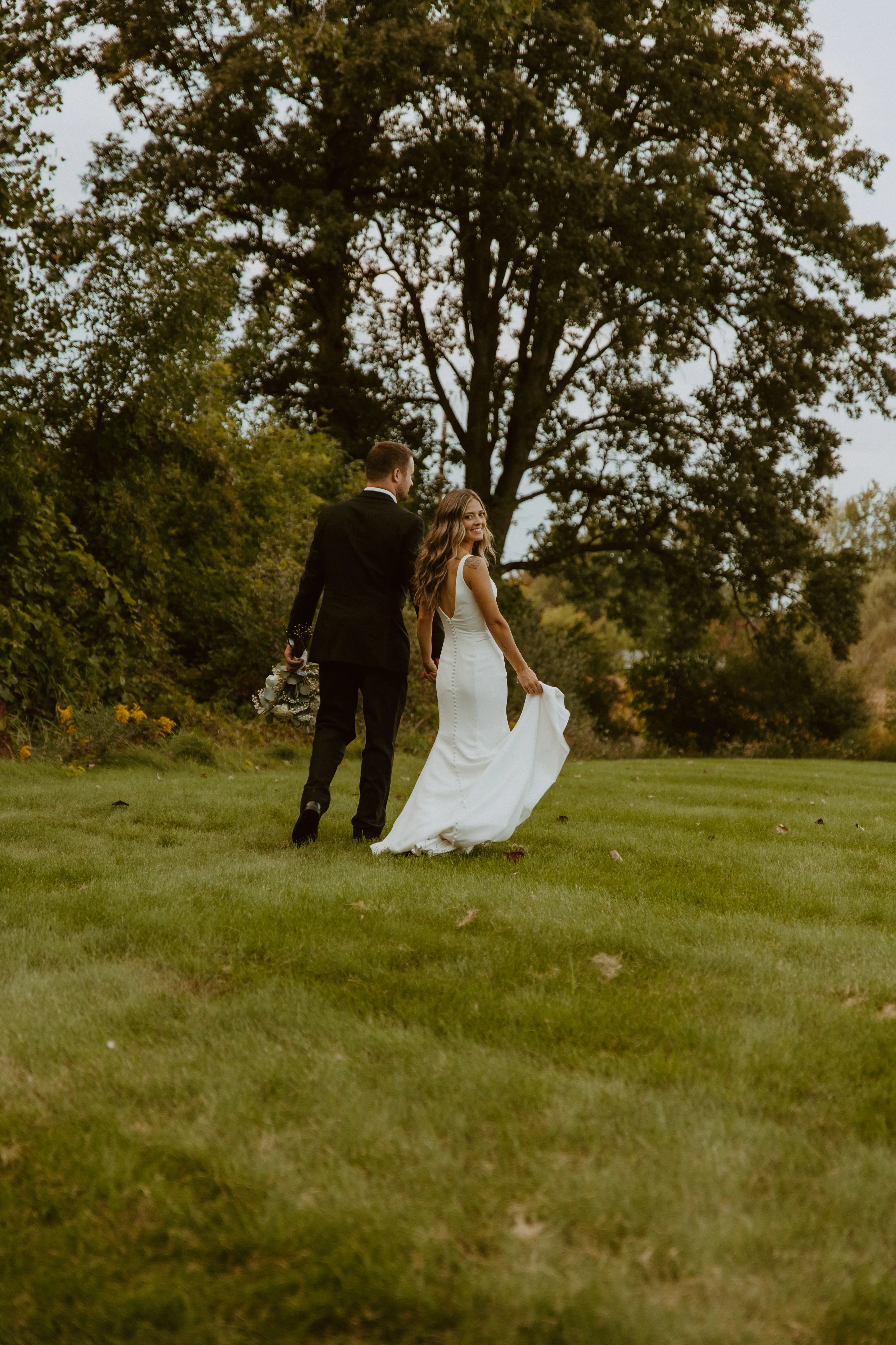 Bride Wearing Simple Fit-and-Flare Wedding Dress Called Fernanda By Maggie Sottero Walking With Groom