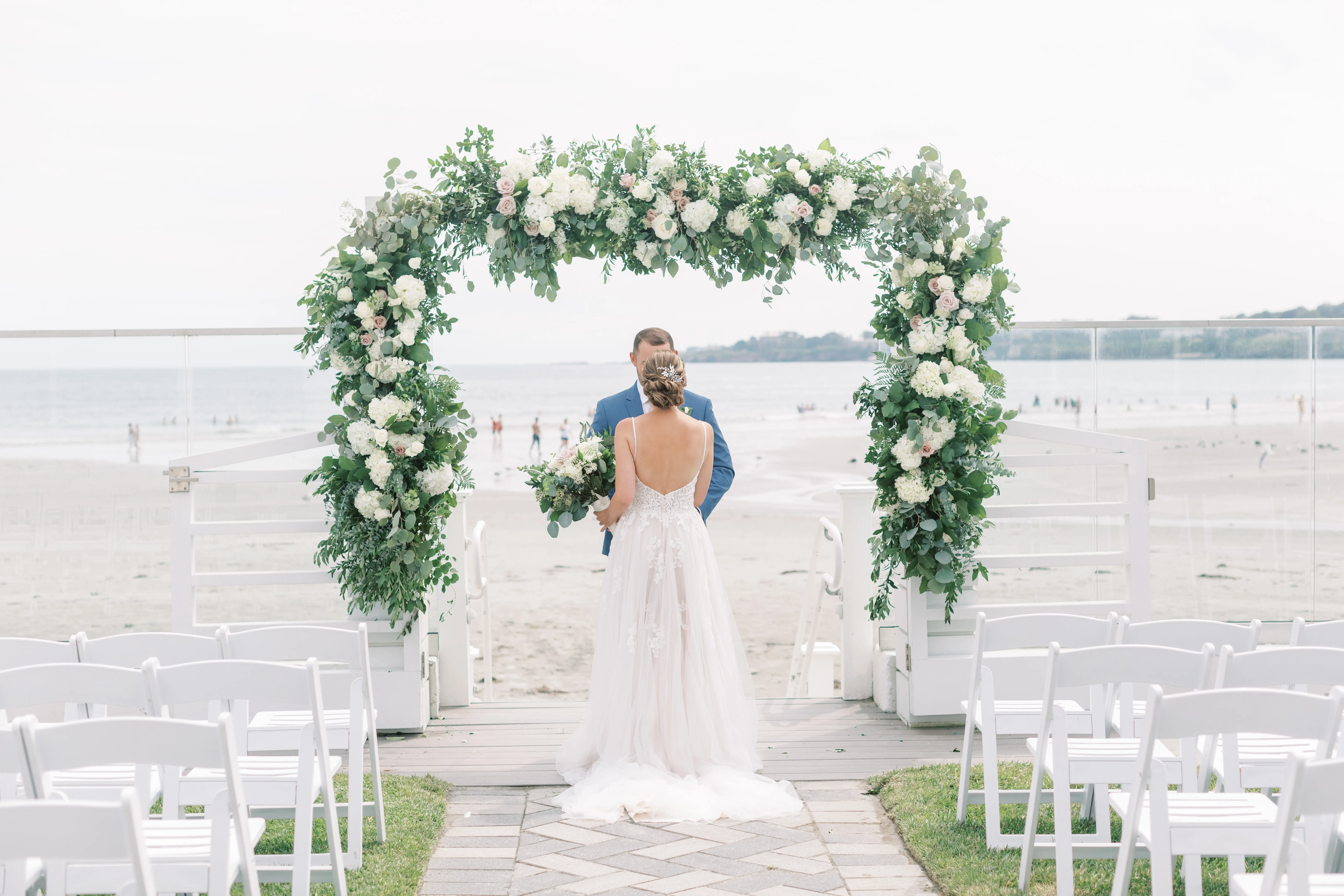Bride Wearing Boho Sheath Wedding Dress Called Marisol By Rebecca Ingram With Groom On The Beach