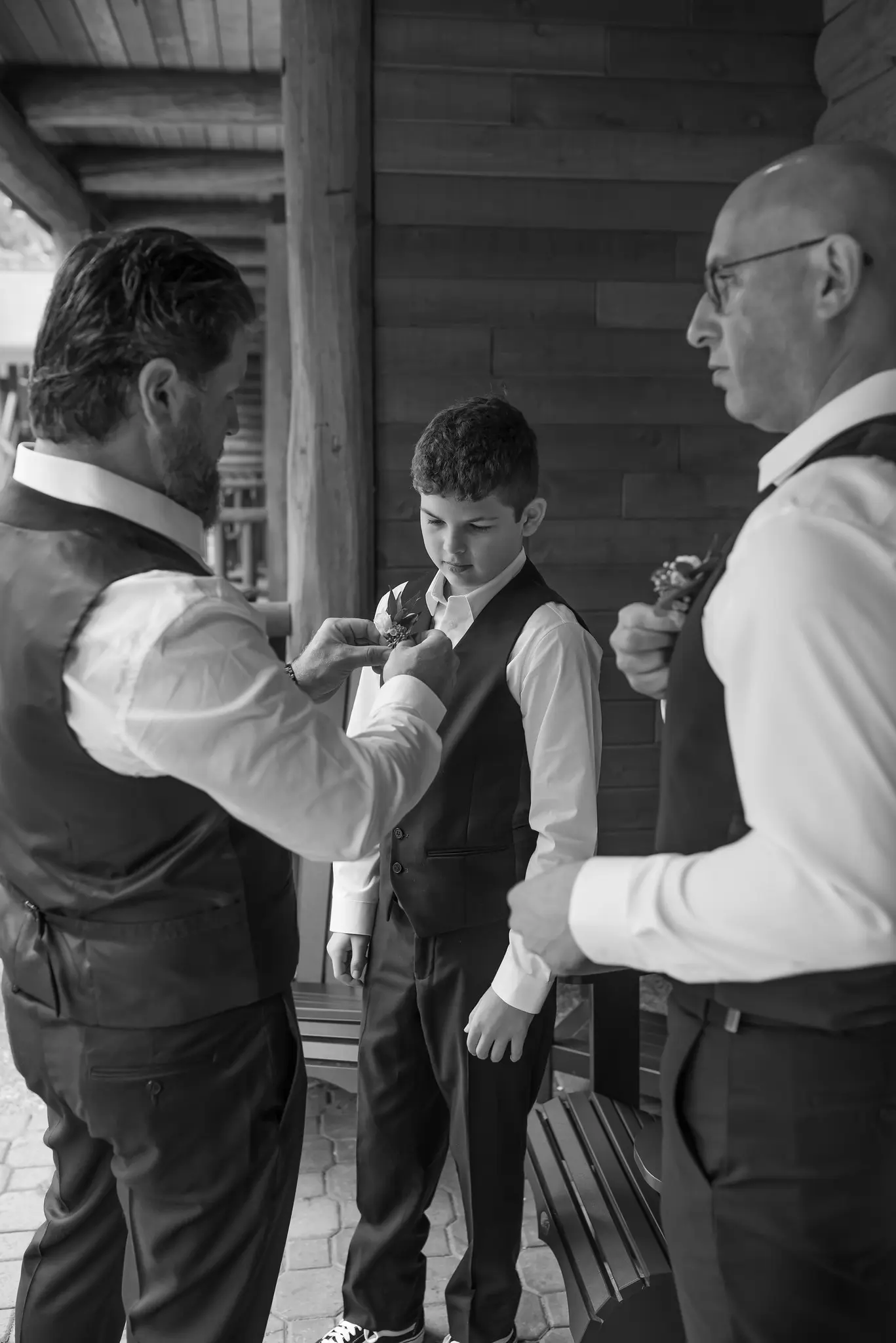 Groomsen helping a boy get ready for the wedding by pinning his boutonniere