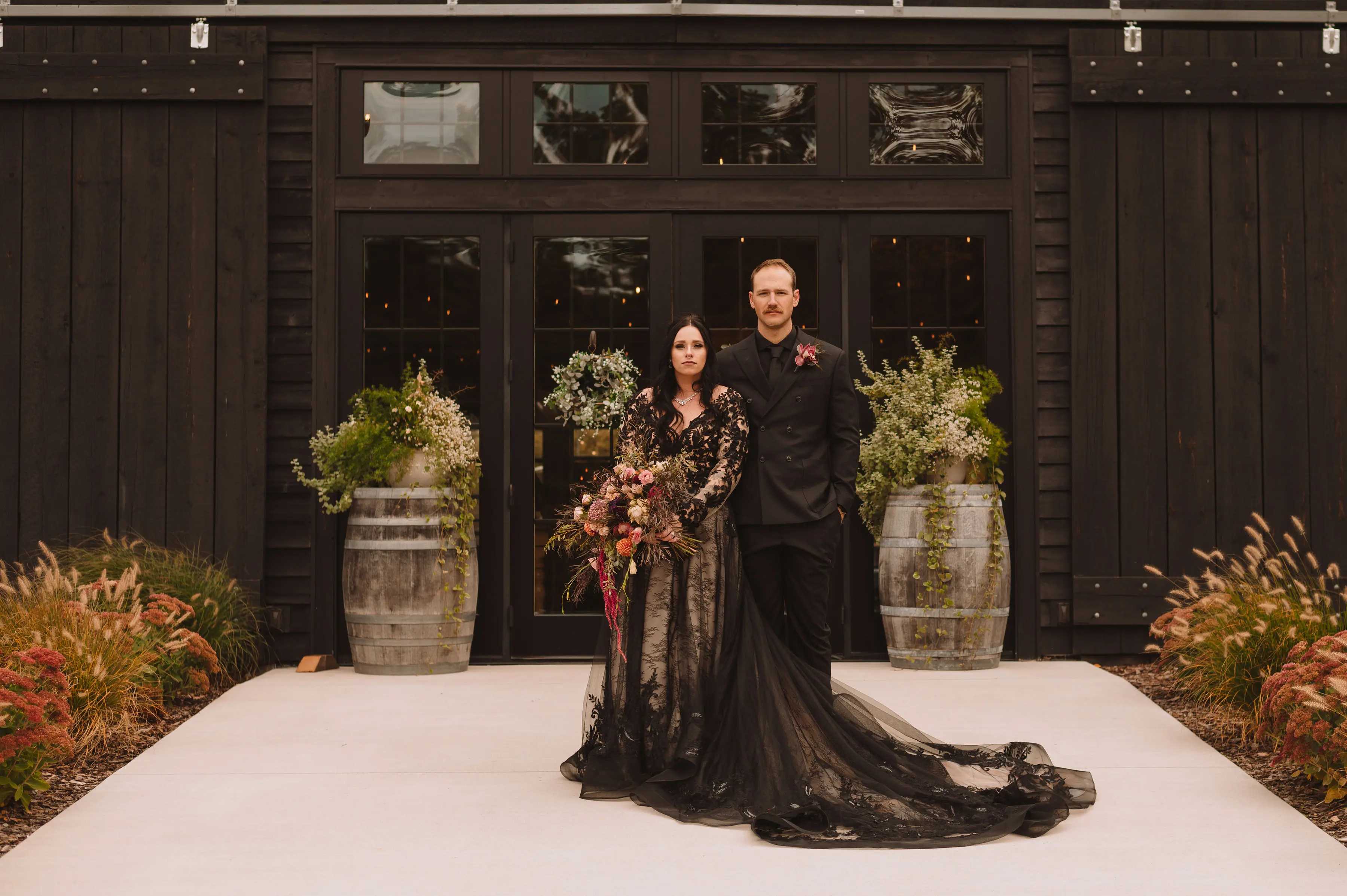 Bride Wearing Black Lace Wedding Dress Called Zander By Sottero And Midgley With Groom In Front Of A Black Building