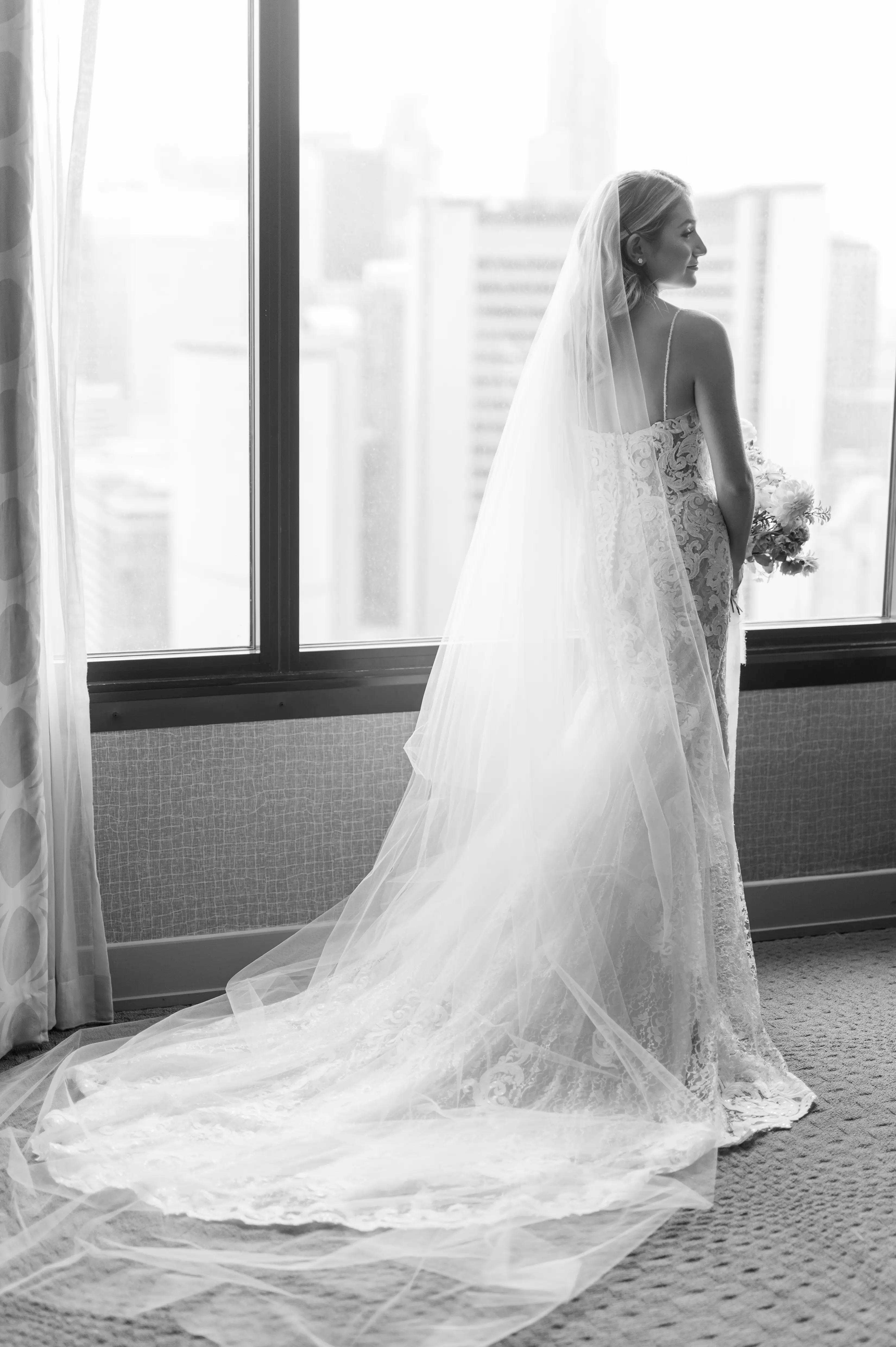 Bride Wearing A Lace Sheath Wedding Gown Named Tuscany Lynette By Maggie Sottero Bride In Front of Window