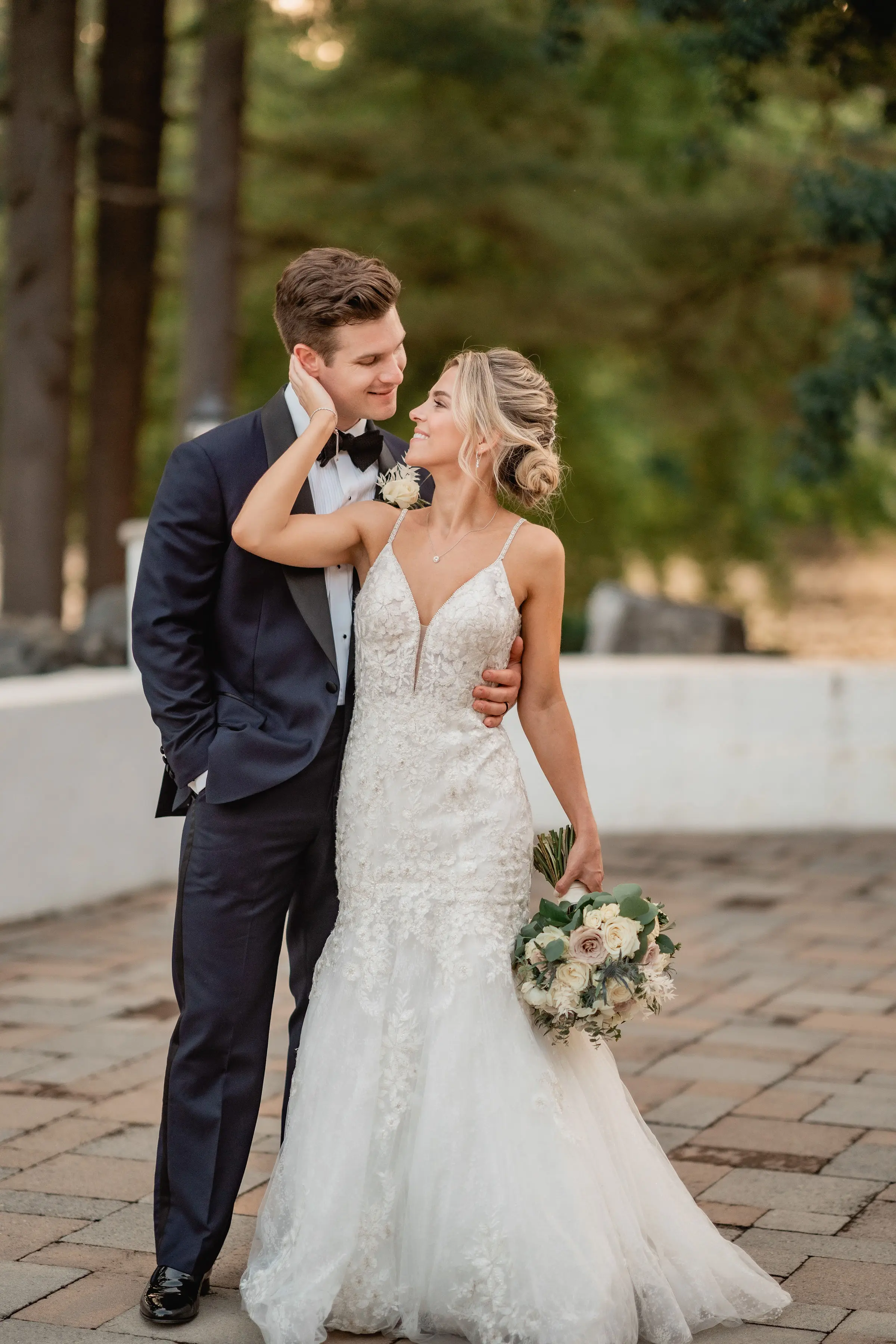 Bride holding grooms face smiling.