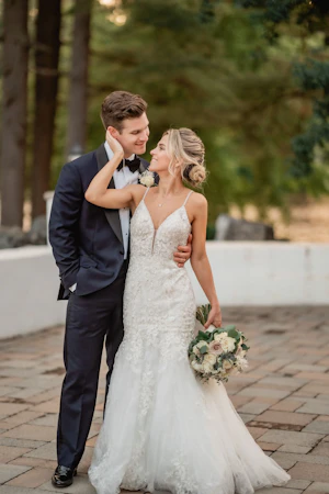 Bride holding grooms face smiling.