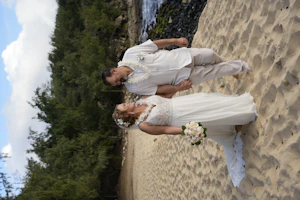 Bride wearing Lorraine wedding dress by Rebecca Ingram holding hands on the beach with her husband