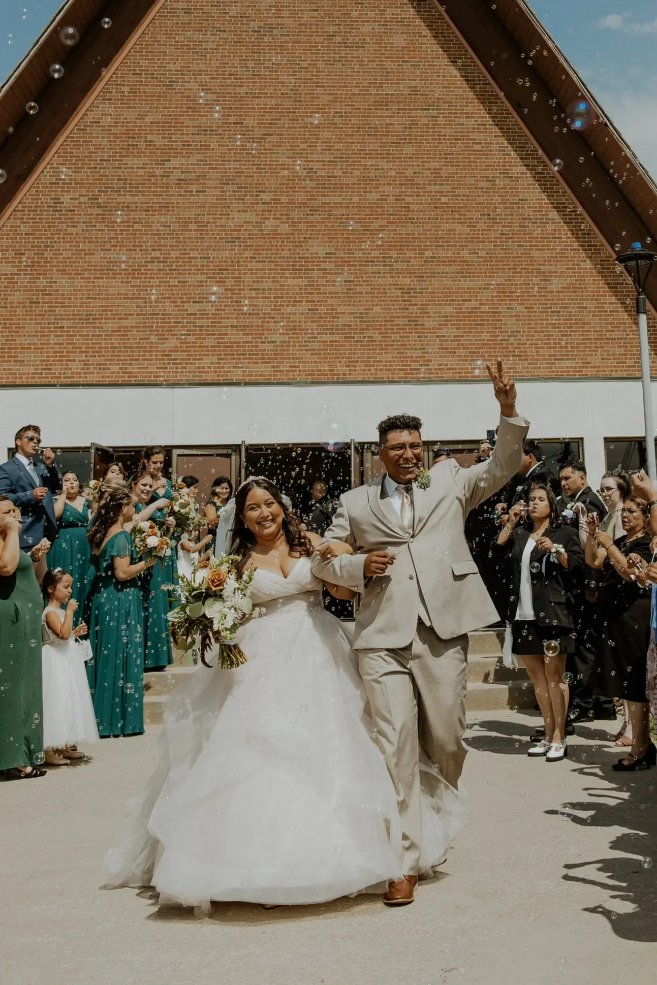 Bride Wearing Tiered Princess Skirt Wedding Dress Called Yasmin By Maggie Sottero Walking With Groom Through Bubbles