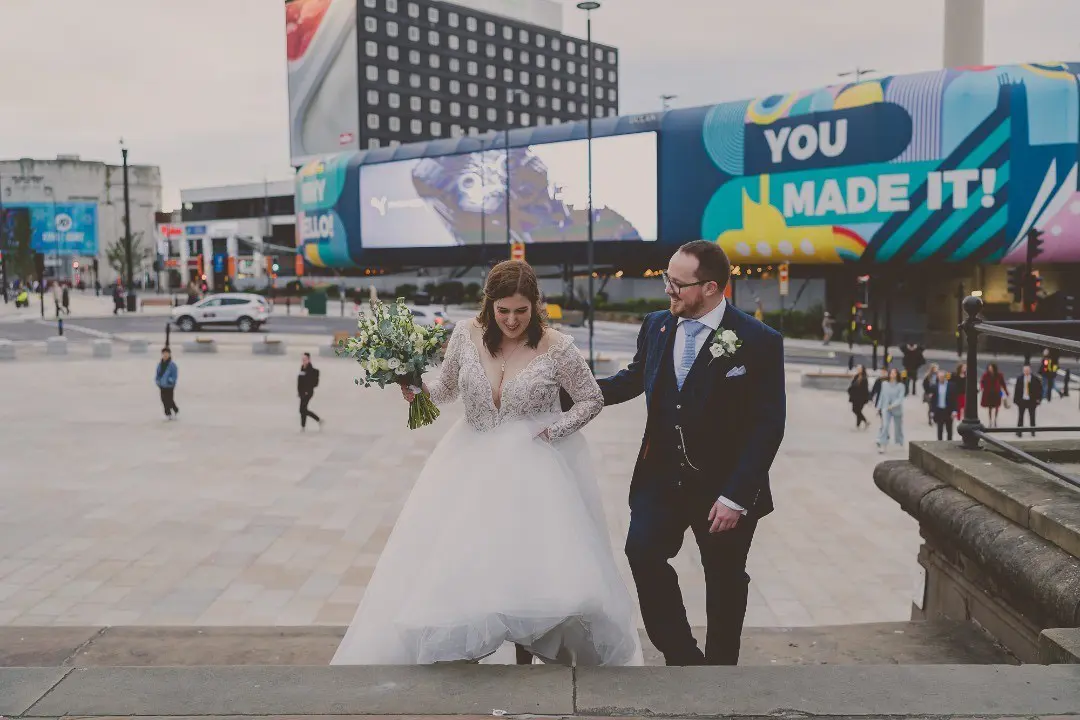 Bride And Groom Walking. Bride Wearing Lace Long Sleeve Ball Gown Wedding Dress With Tulle Skirt Called Mallory Dawn By Maggie Sottero