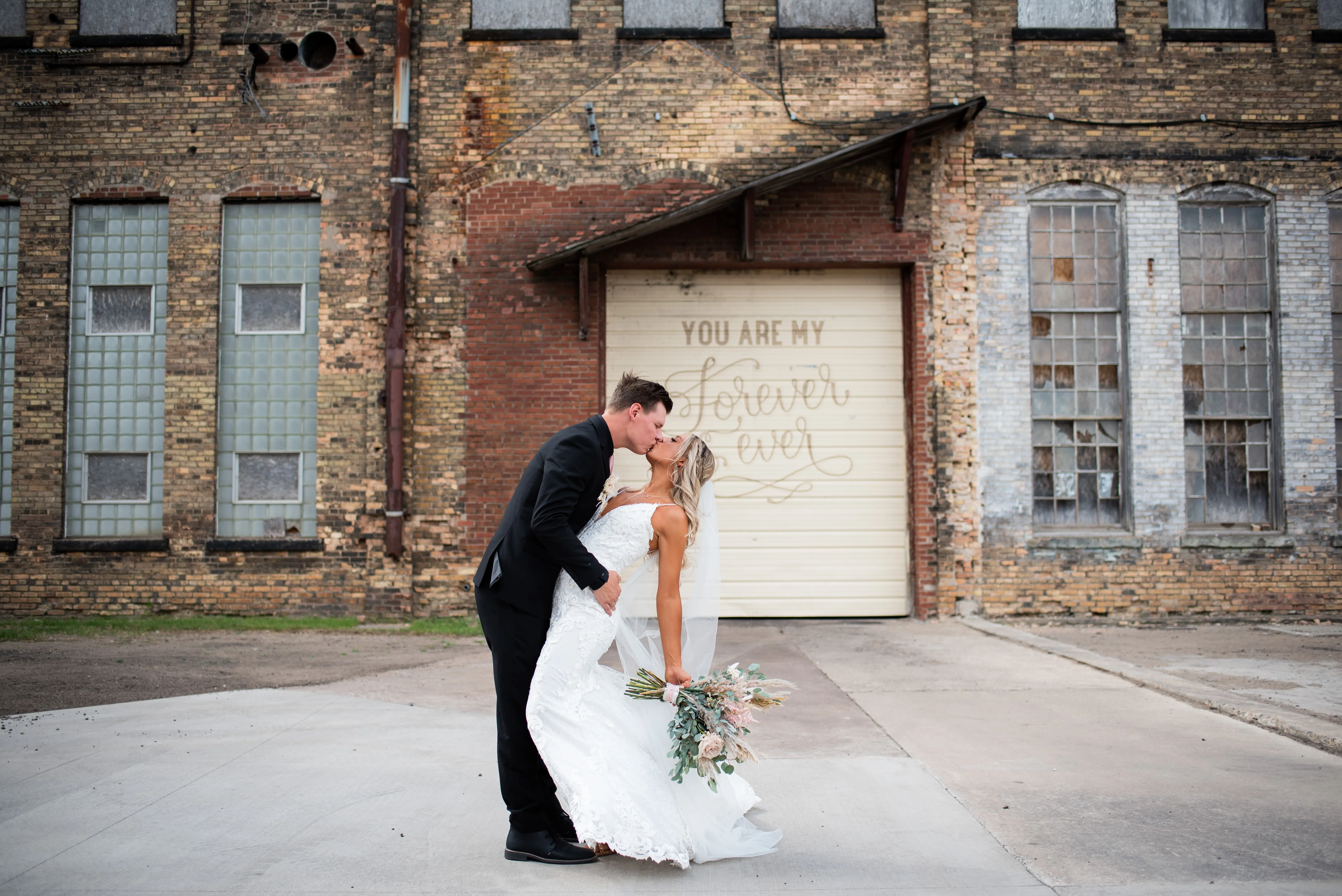 Bride with groom wearing romantic lace sheath wedding dress.