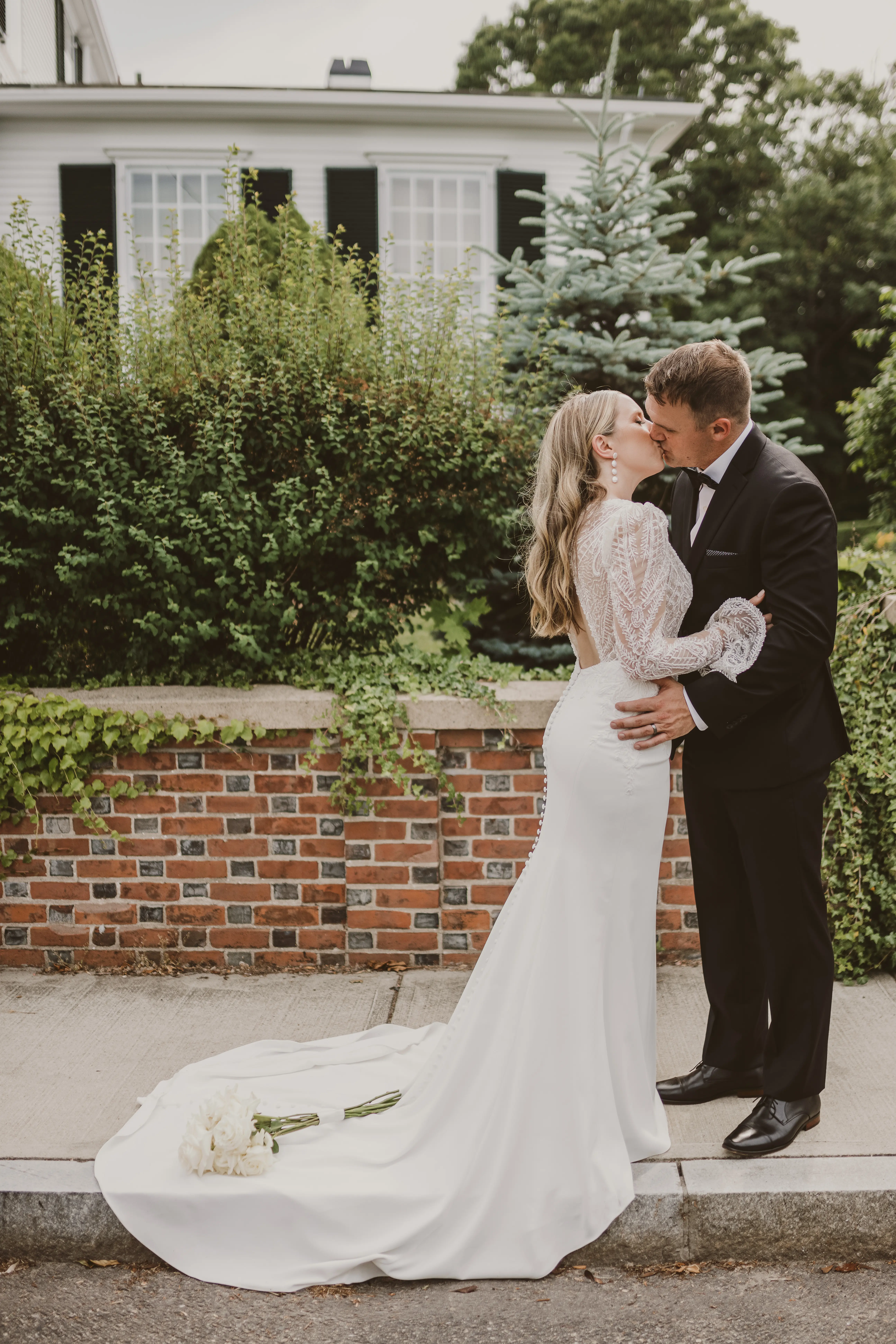 Bride and groom kissing with the ivory bouquet rested on her train.