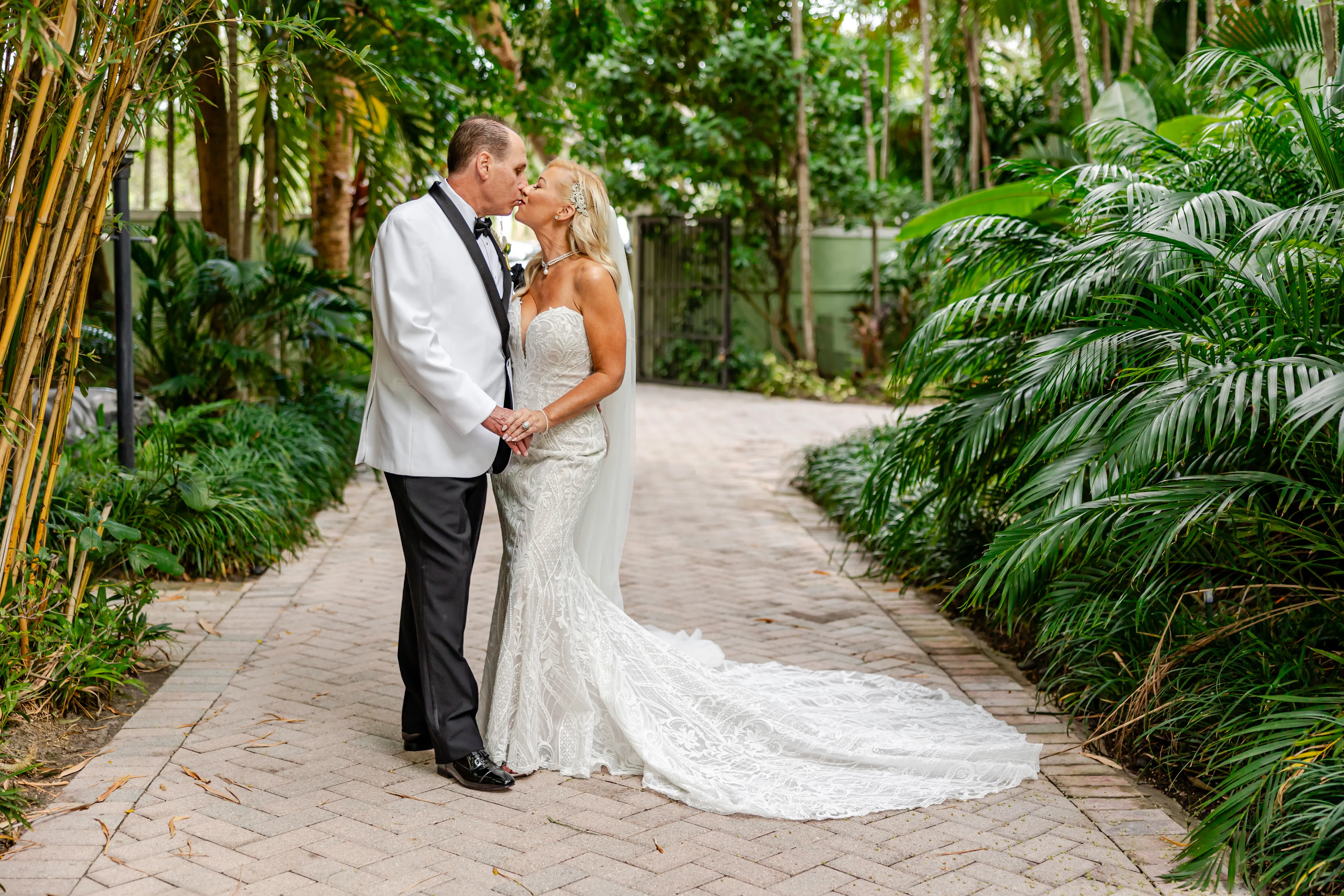 Bride Wearing Lace Mermaid Wedding Dress Called Bronson By Sottero And Midgley Kissing Groom In A Garden