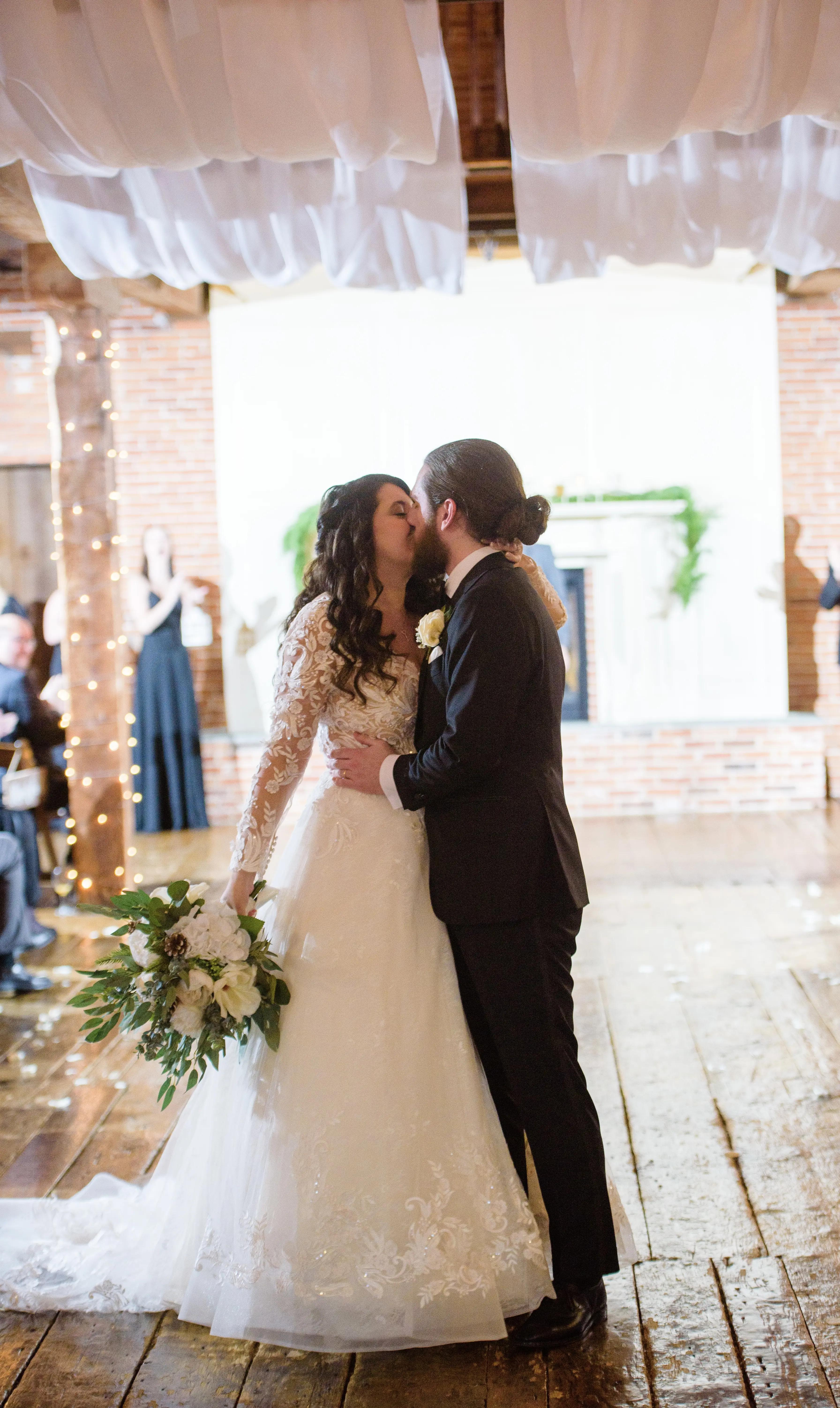 Bride And Groom Kiss. Bride Wearing Lace Long Sleeve Wedding Dress Called Zander By Sottero And Midgley