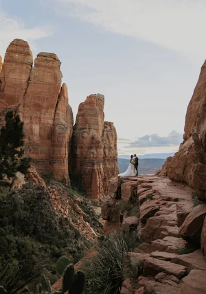 Groom Kissing Bride In Floral Wedding Dress Named Lettie By Rebecca Ingram Surrounded By Red Rocks
