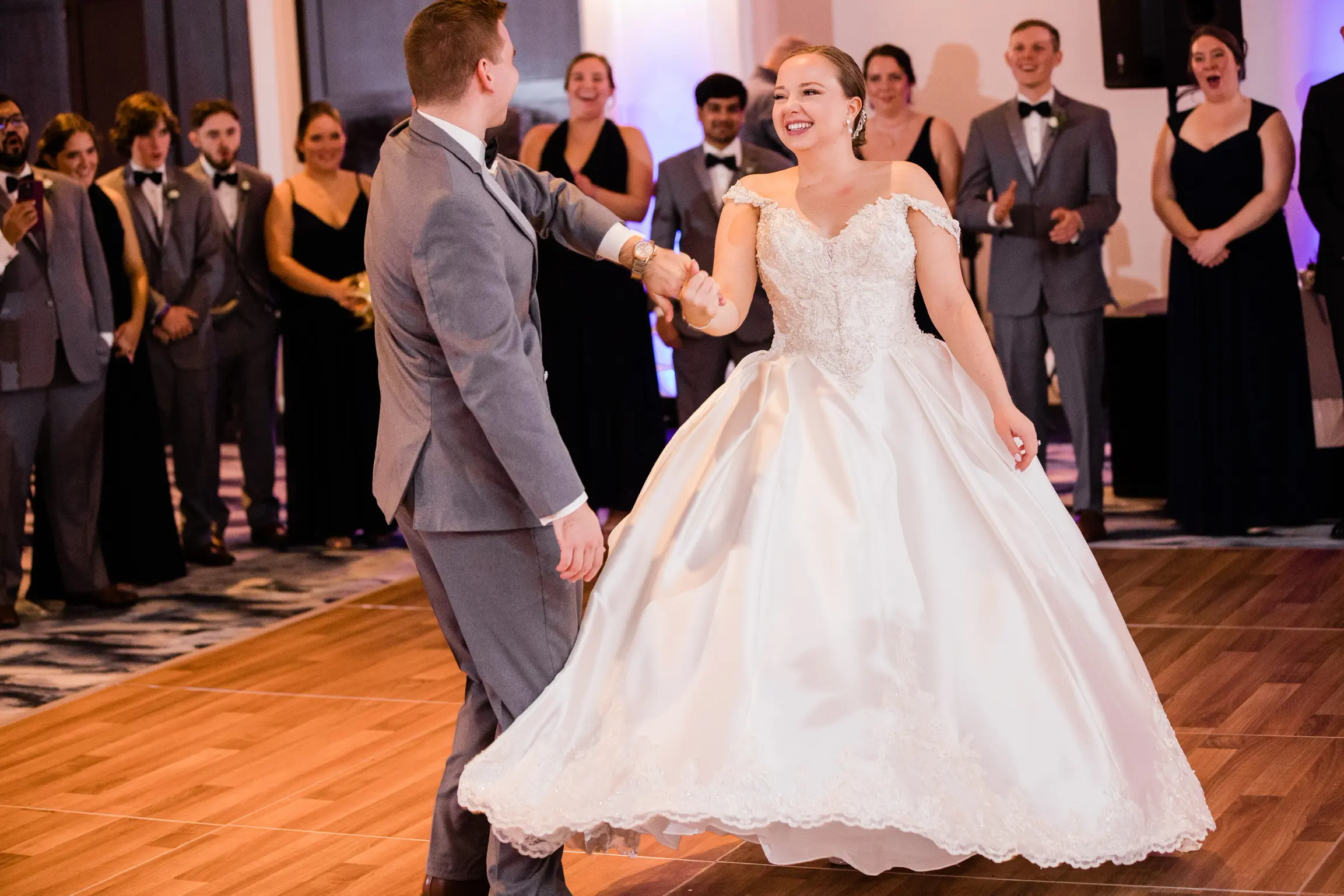 Bride And Groom Dancing. Bride Wearing Off-The-Shoulder Glamorous Ball Gown Called Kimora By Sottero And Midgley