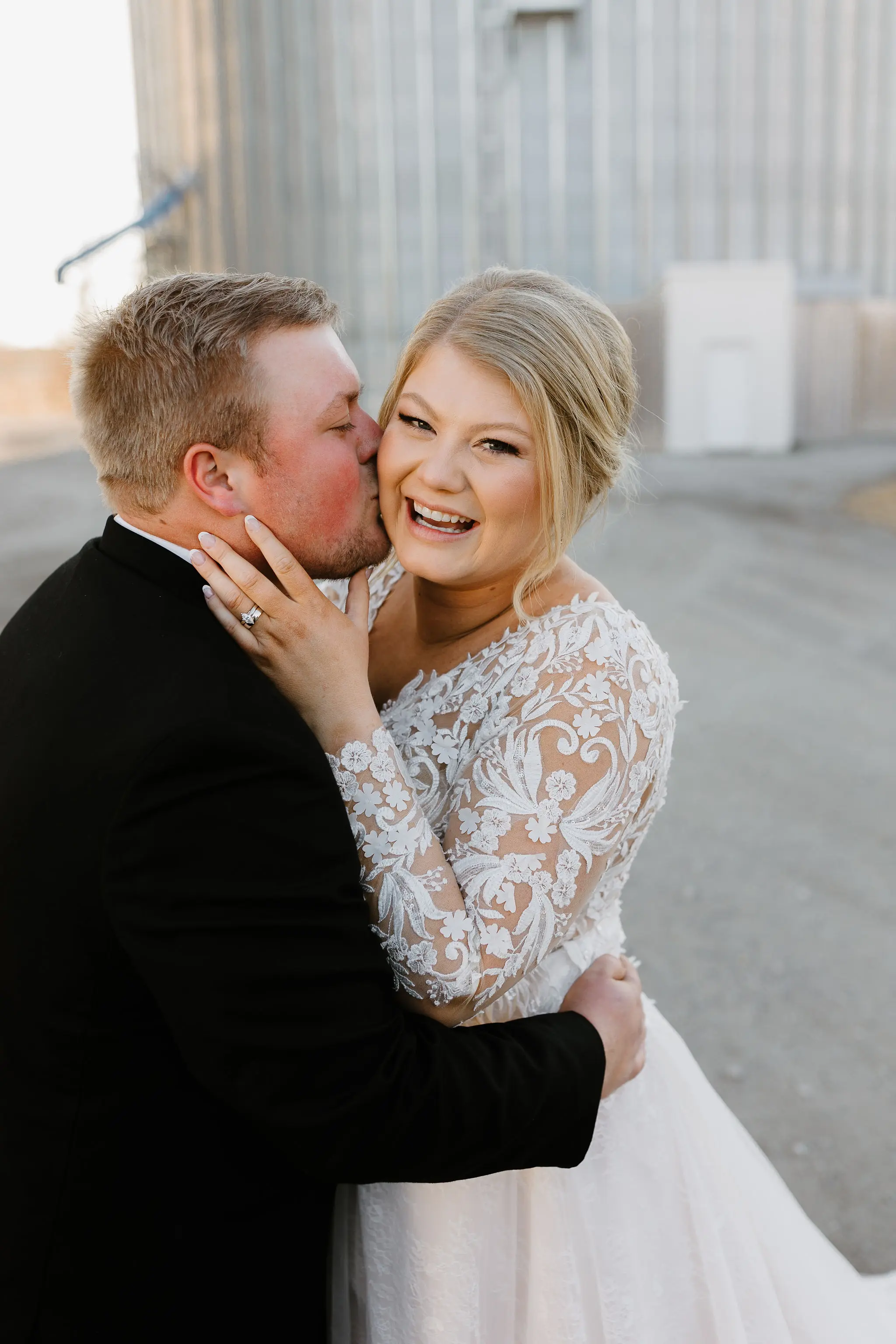 Bride And Groom Together. Bride Wearing Layered Ball Gown Wedding Dress With Lace Long Sleeves Called Zander By Sottero And Midgley