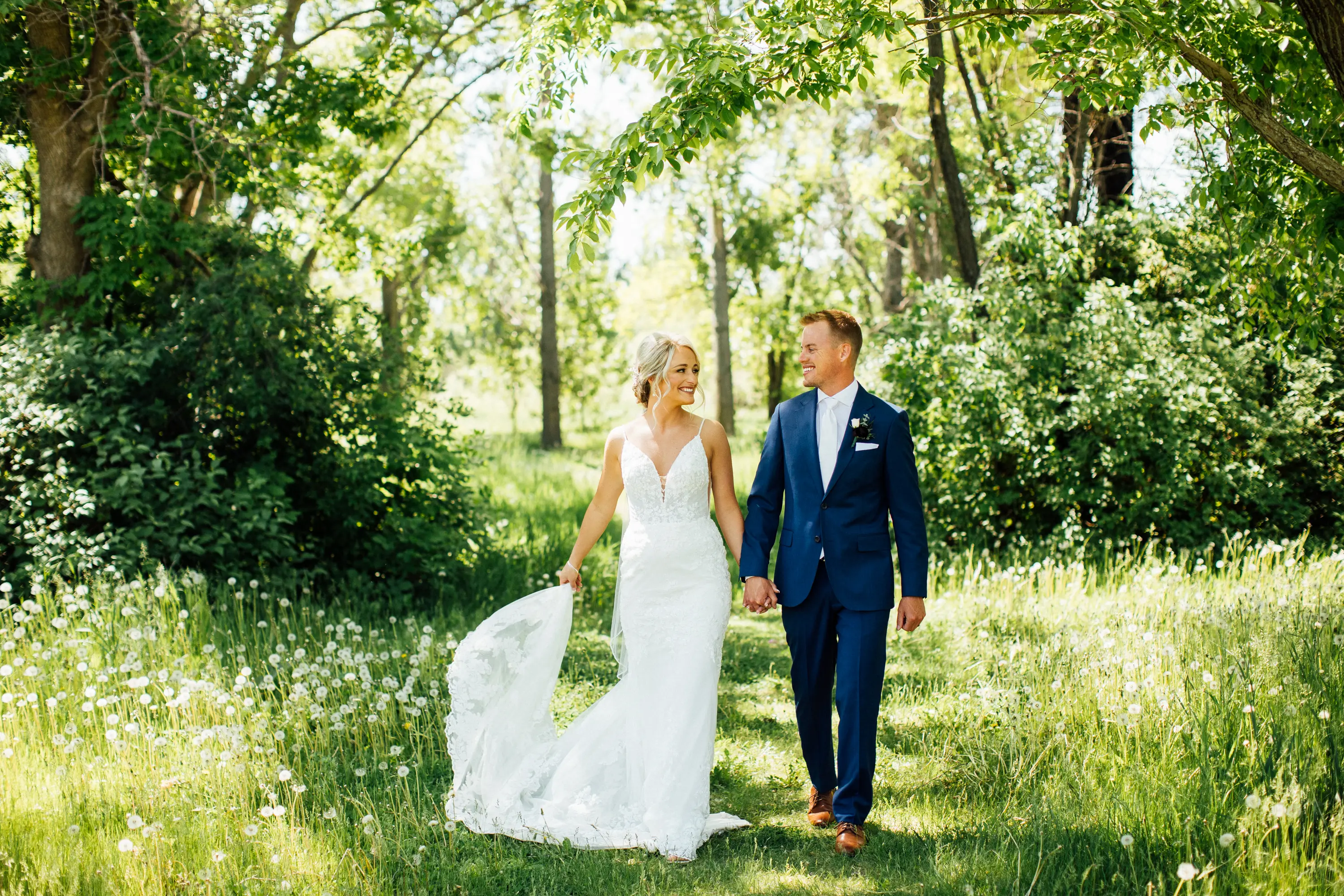 Bride Wearing Graceful Sparkly Lace Wedding Dress Called Fontaine By Maggie Sottero Walking With Groom Through Trees