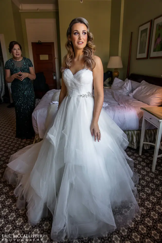 Bride wearing strapless ballgown tulle wedding dress with sweetheart neckline indoors.