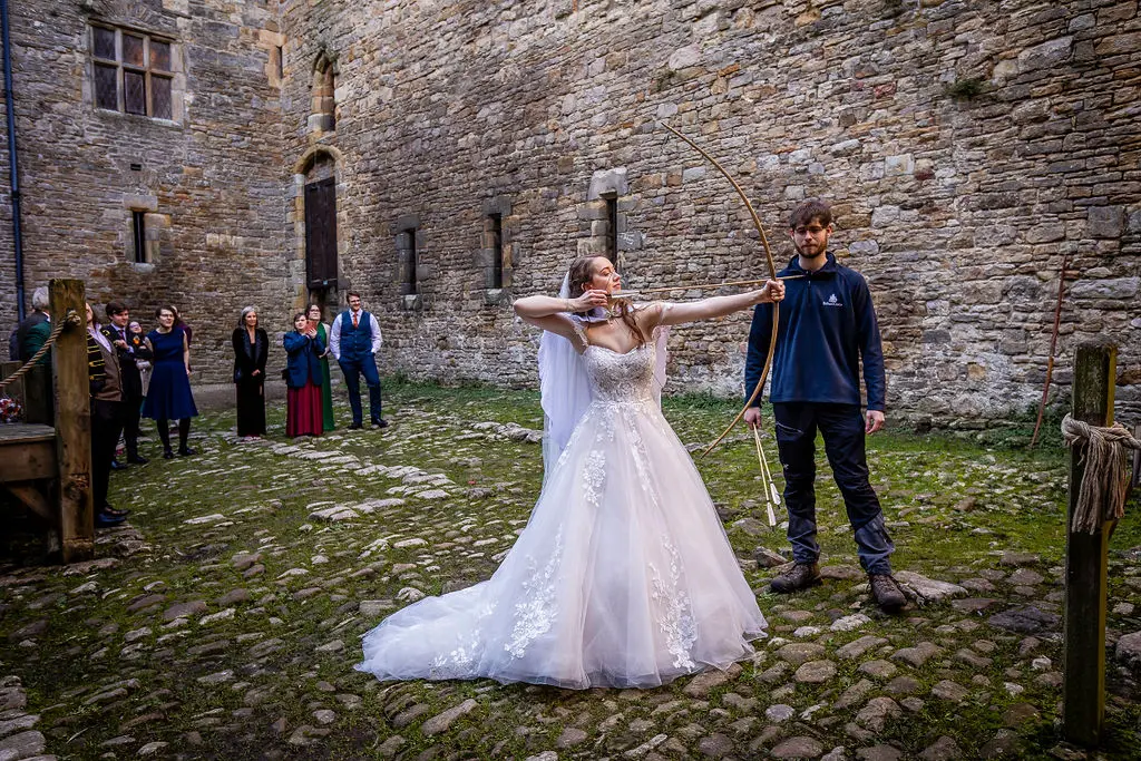 Bride Wearing Princess Ballgown Harlem By Maggie Sottero Shooting A Bow And Arrow