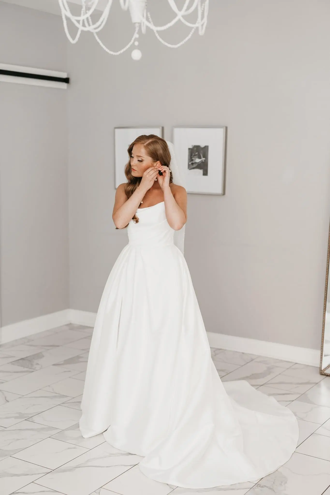 Bride wearing Aspen by Sottero and Midgley putting in earrings