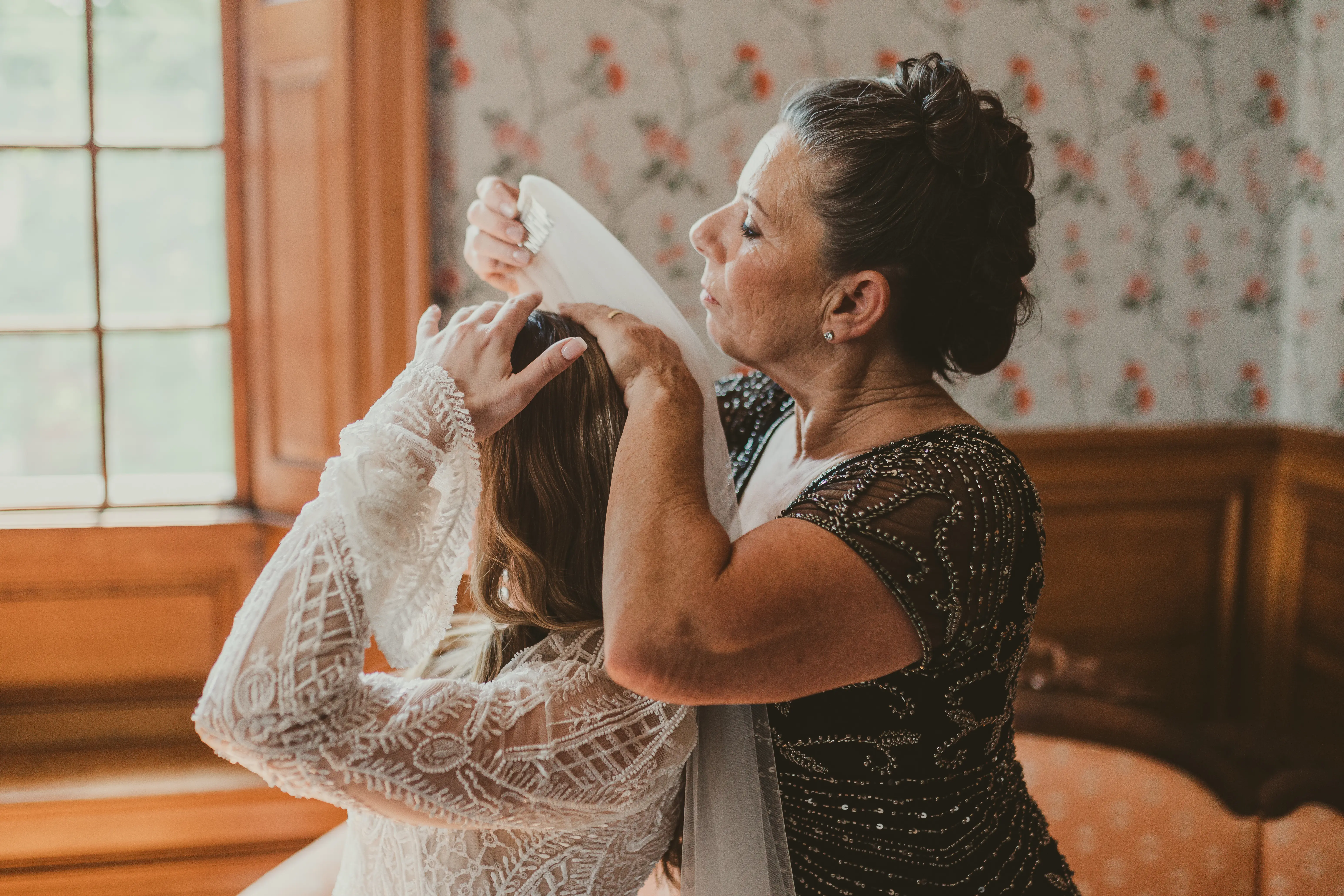 Mother of the bride putting the veil carefully in her hair.