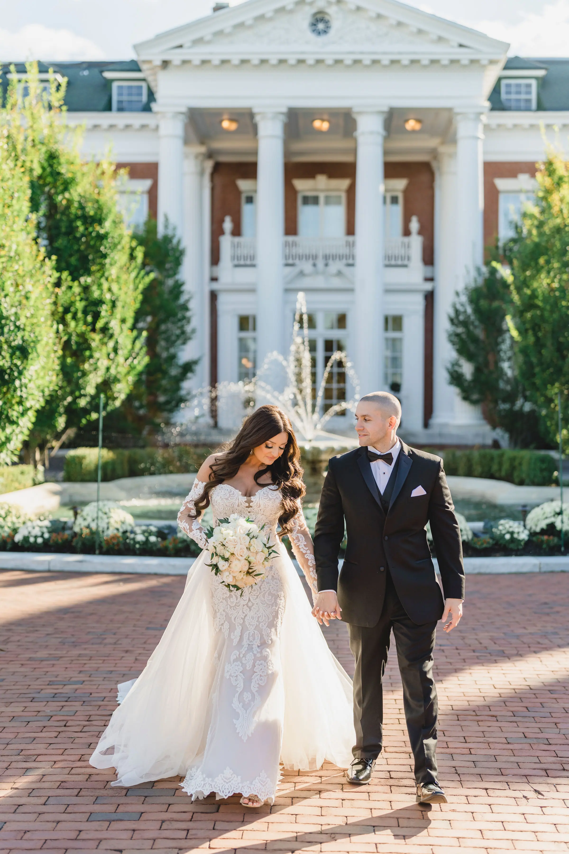 Bride Wearing Sparkly Lace Fit-and-Flare Wedding Dress Walking with Groom Outdoors.