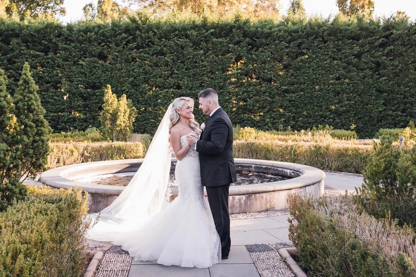Bride Wearing Lace Mermaid Wedding Dress Called Alistaire By Maggie Sottero With Groom Next To A Fountain