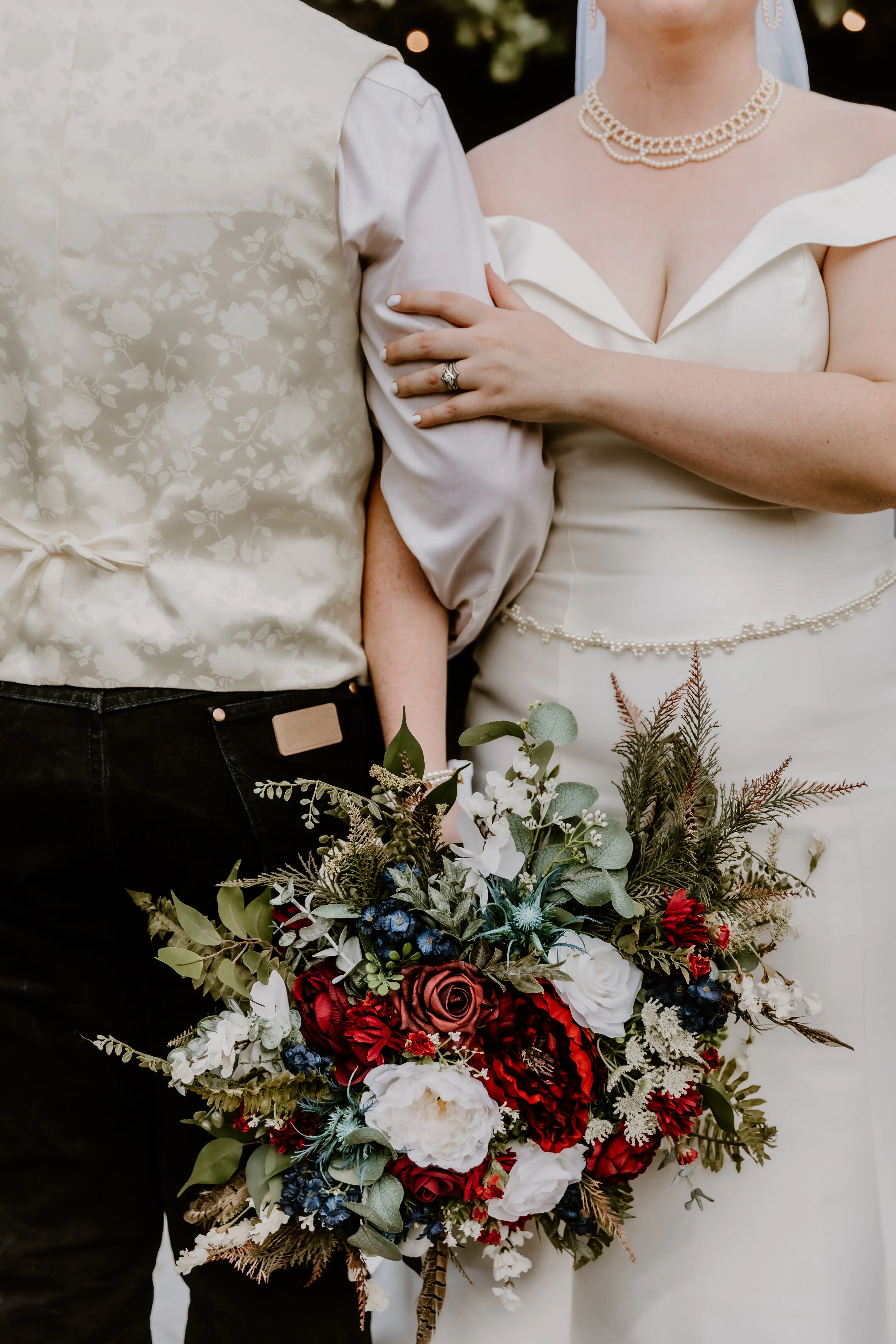 Bride Wearing Simple Fit And Flare Wedding Dress Called Josie By Rebecca Ingram Holding Groom and A Red White And Blue Bouquet