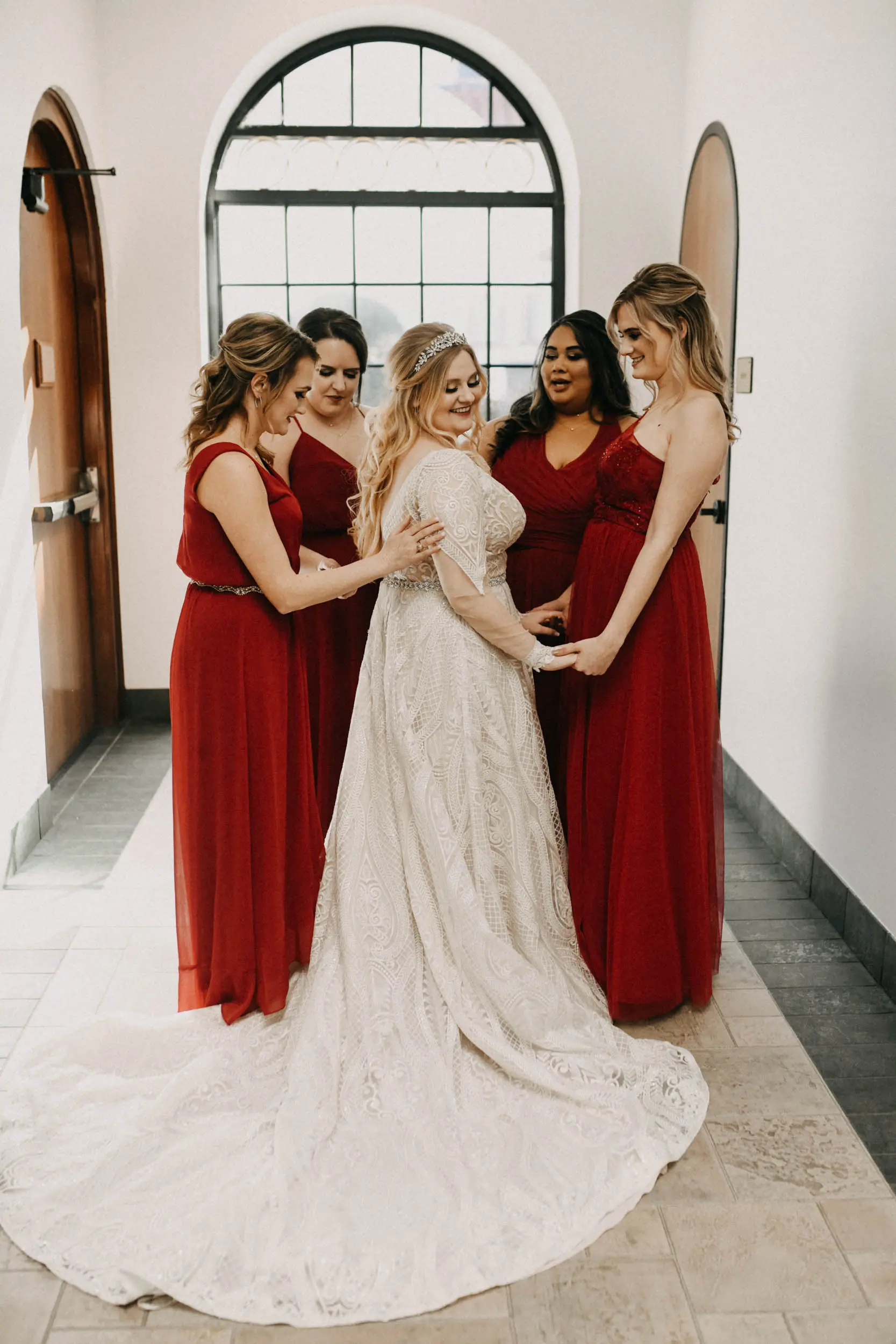 Bride wearing wedding dress called Roxanne with bridesmaids in red.
