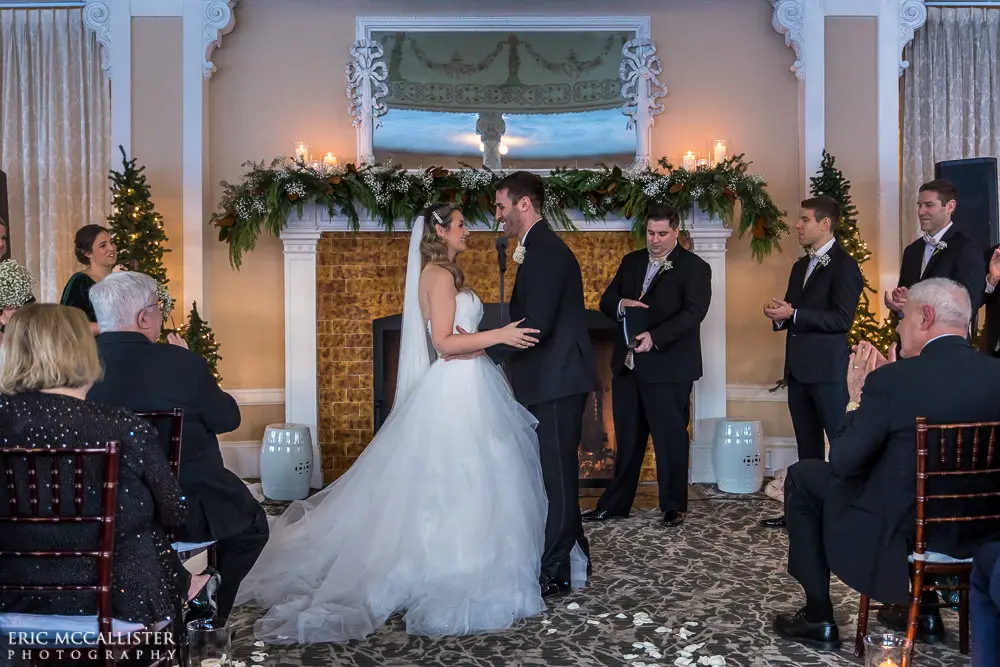 Bride with groom wearing strapless ballgown tulle wedding dress with sweetheart neckline indoors.