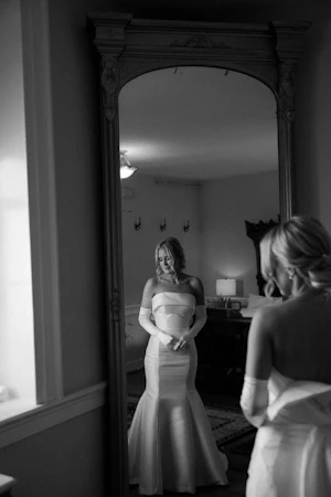 Bride Looking In The Mirror Wearing A White Fit And Flare Wedding Dress Named Mitchell By Maggie Sottero