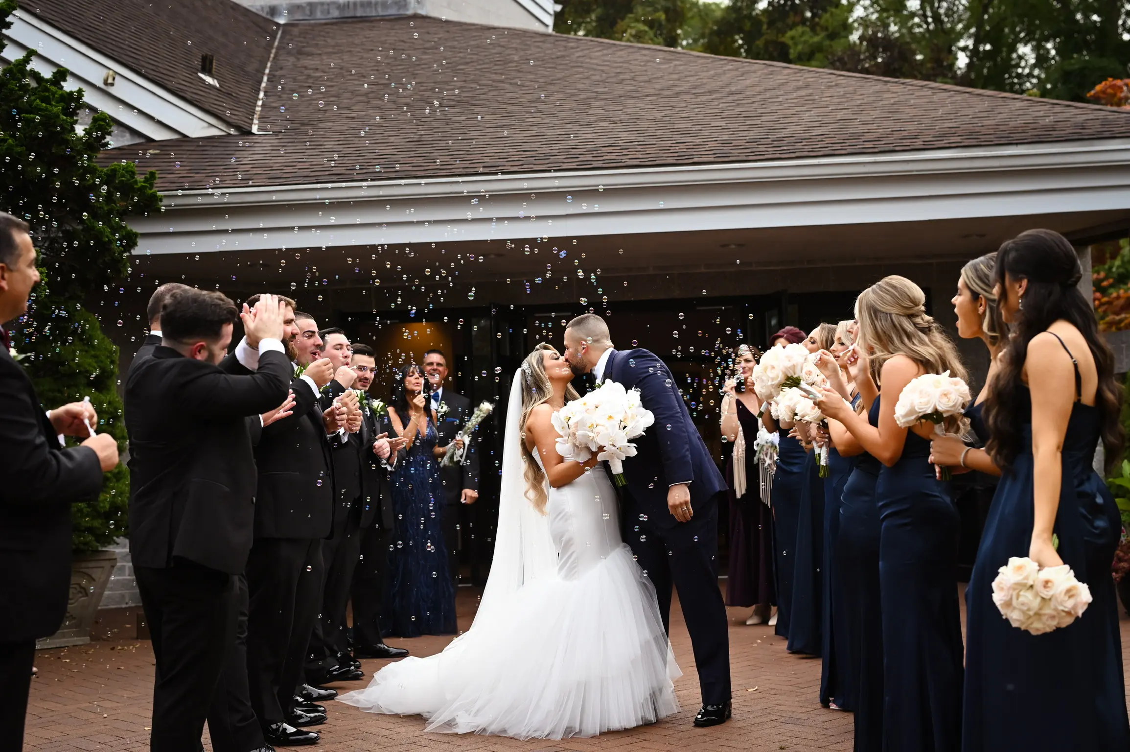 Bride wearing Holden wedding dress by Sottero and Midgley kissing her husband with bubbles